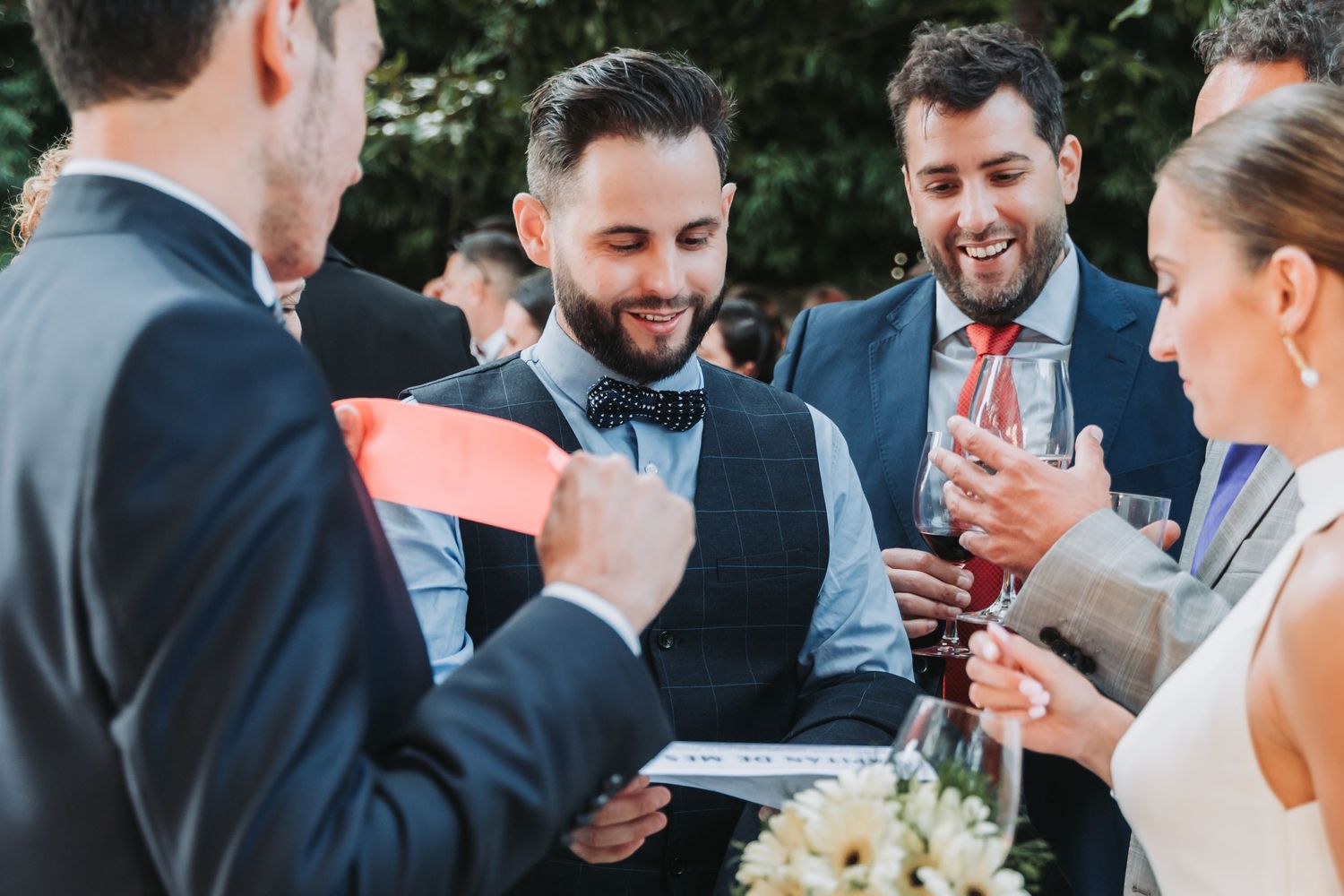 Wedding guests laugh and socialize during an outdoor cocktail reception.