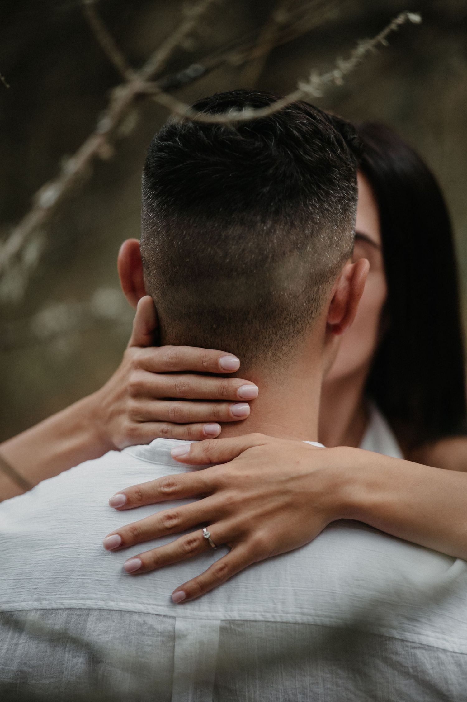 Close-up shot showing hands tenderly embracing around a neck, wearing a white shirt.