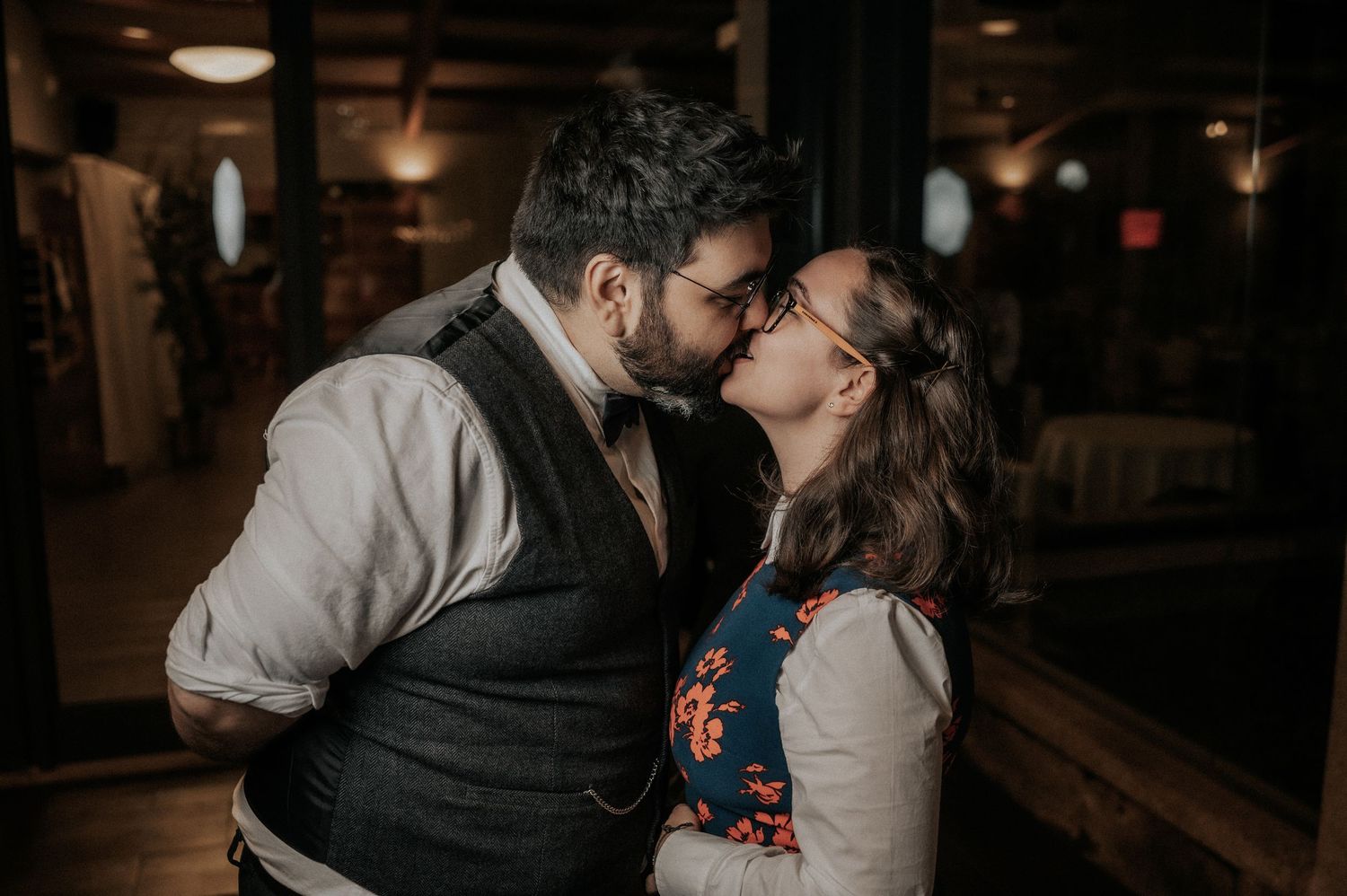 A romantic couple shares an intimate moment in a dimly lit venue during their wedding celebration.