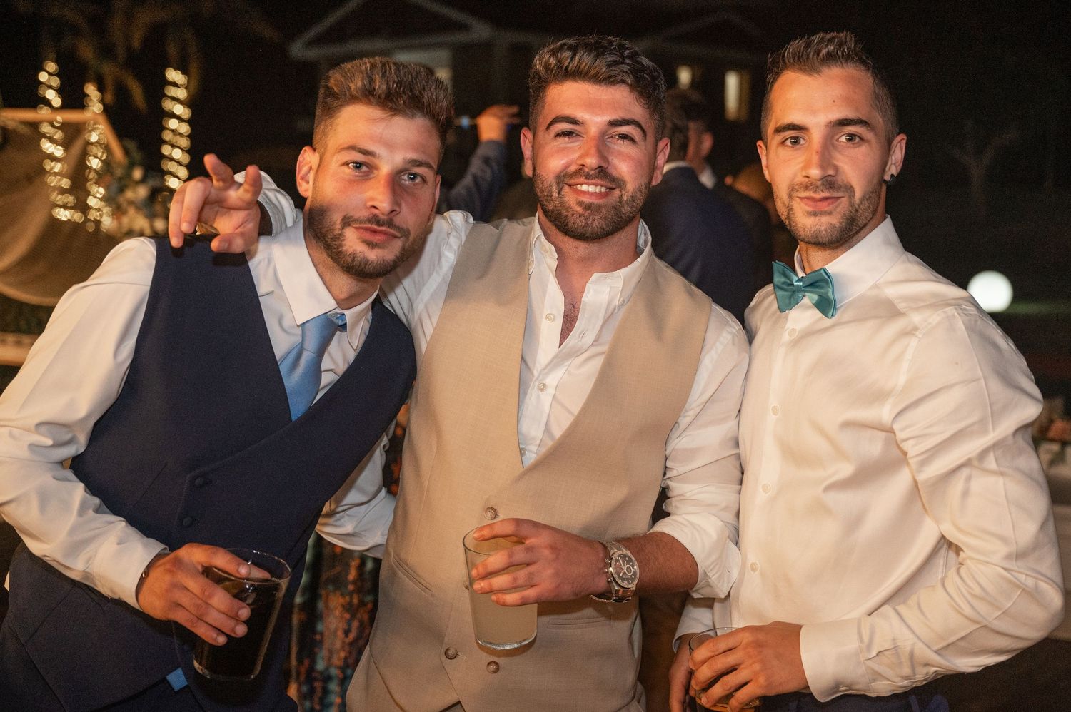 Group of men in formal attire smiling and socializing at an evening party.