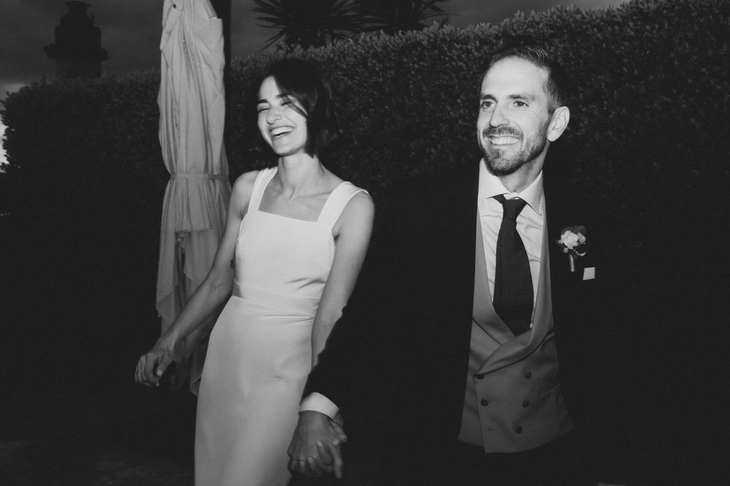 Elegant black and white wedding photo capturing a couple sharing a joyful moment outdoors.