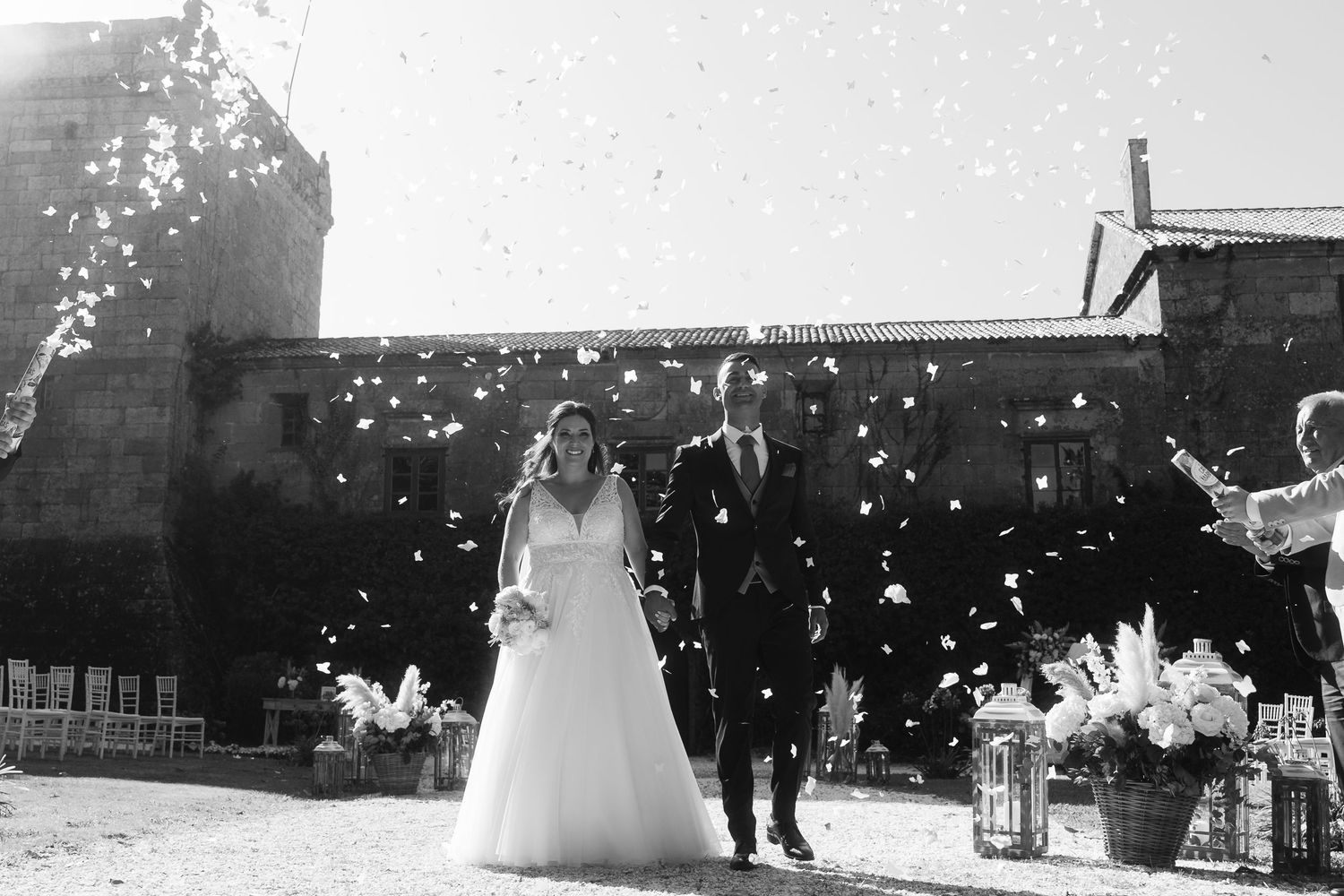 A couple shares a romantic dance under twinkling string lights at an outdoor evening wedding celebration.