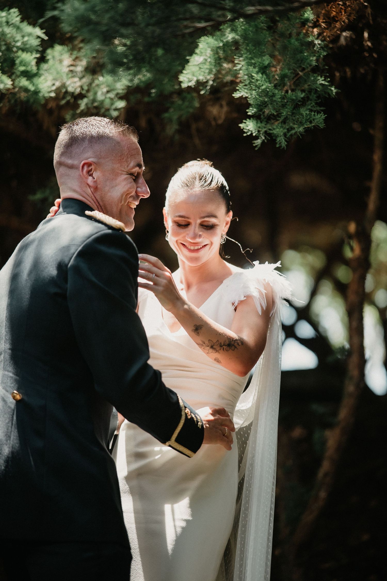 A tender first dance moment between newlyweds in a natural outdoor setting with trees in the background.