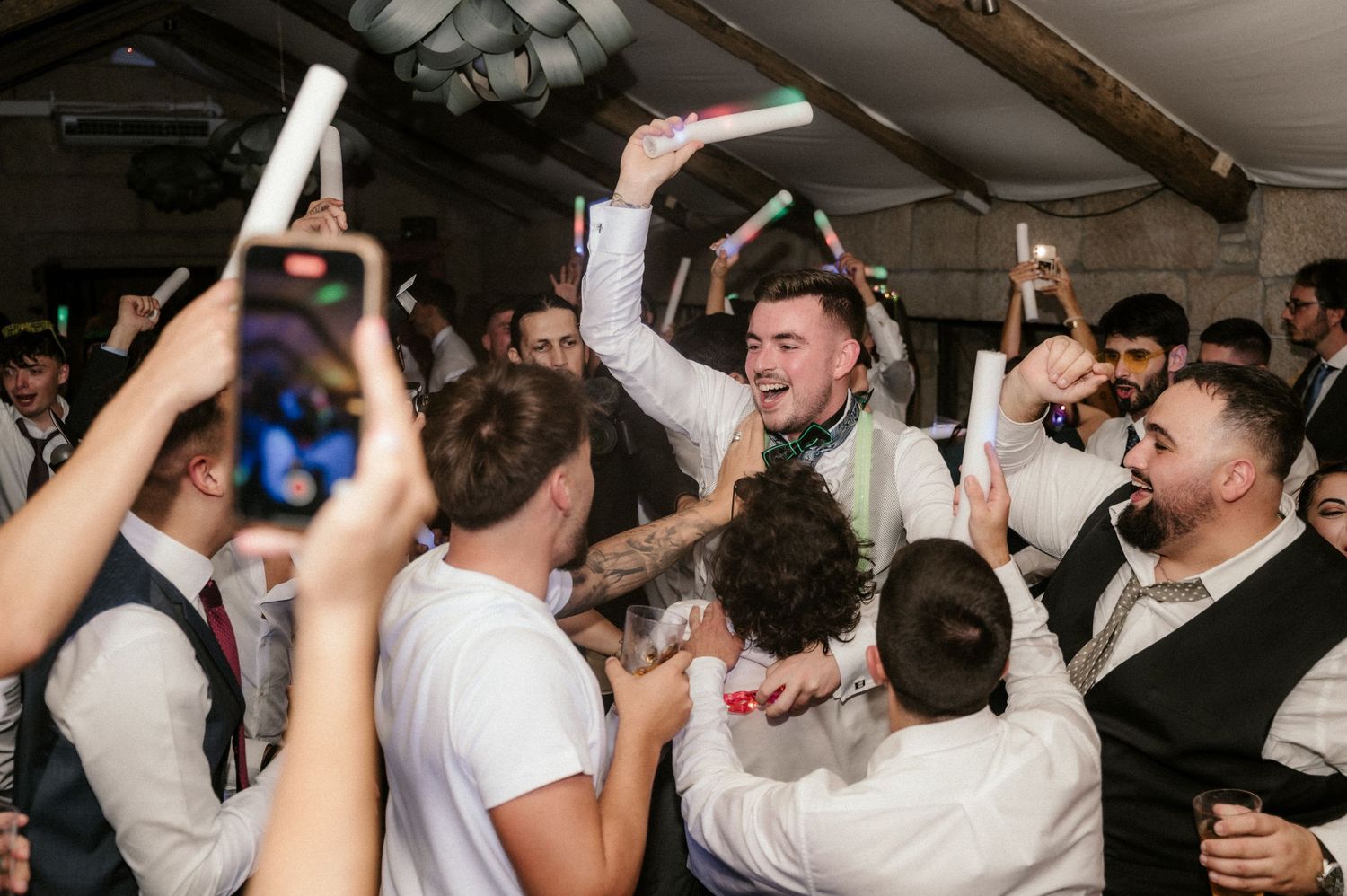 Wedding reception dance floor filled with guests celebrating and dancing under indoor lighting.