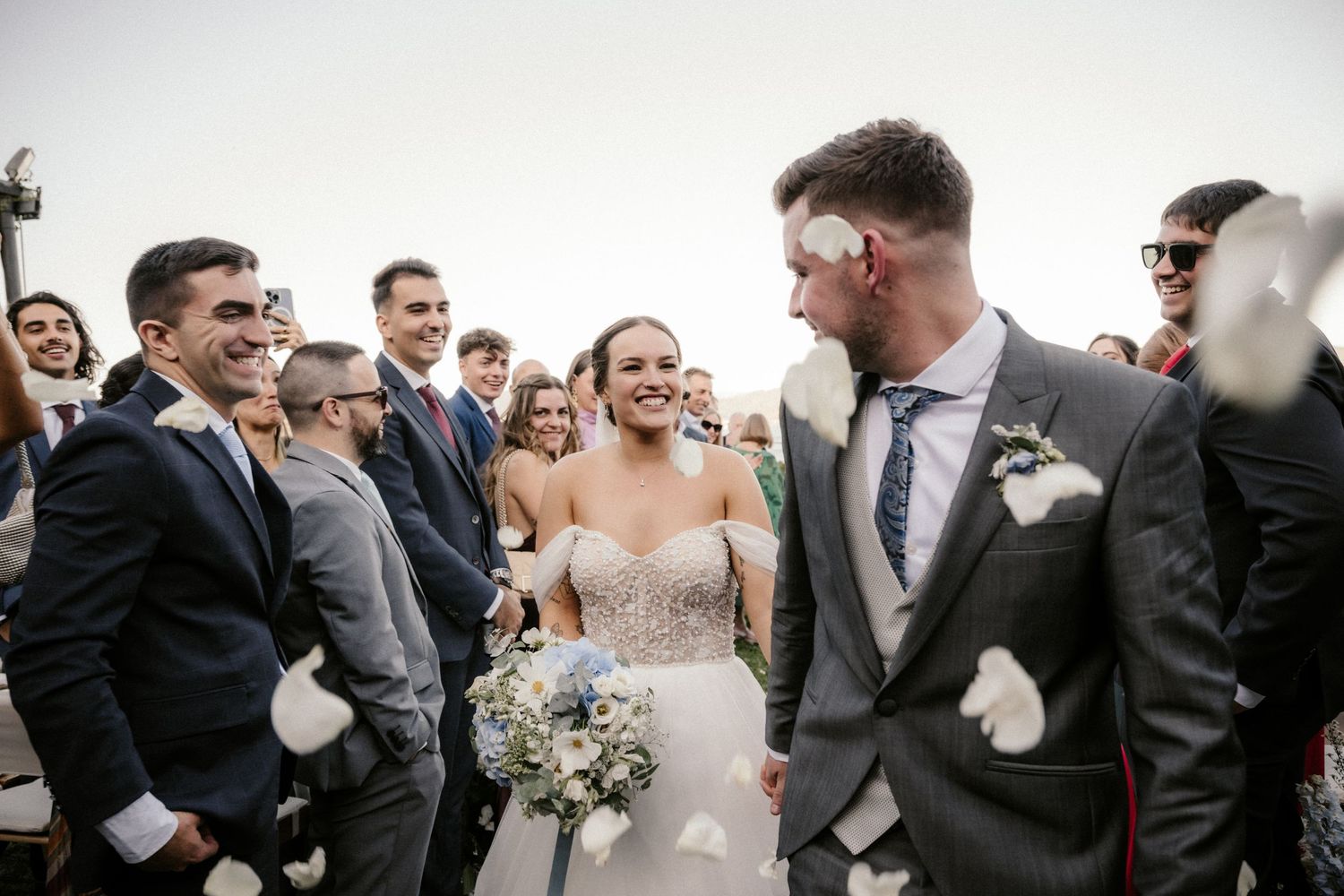 Wedding party members share joyful laughter during an outdoor celebration.