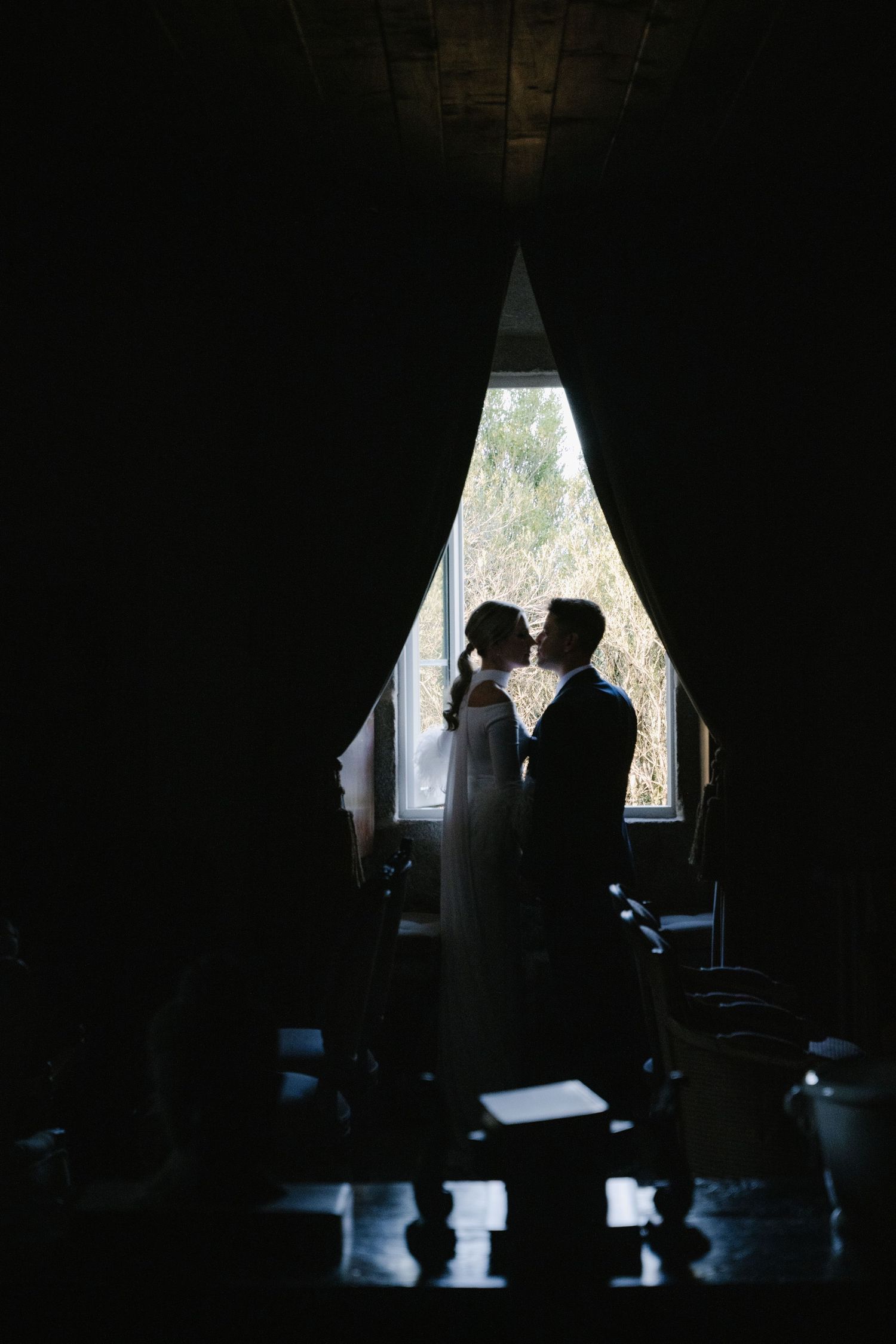 Silhouetted figures stand in front of bright window in moody artistic sequence of dark interior shots.