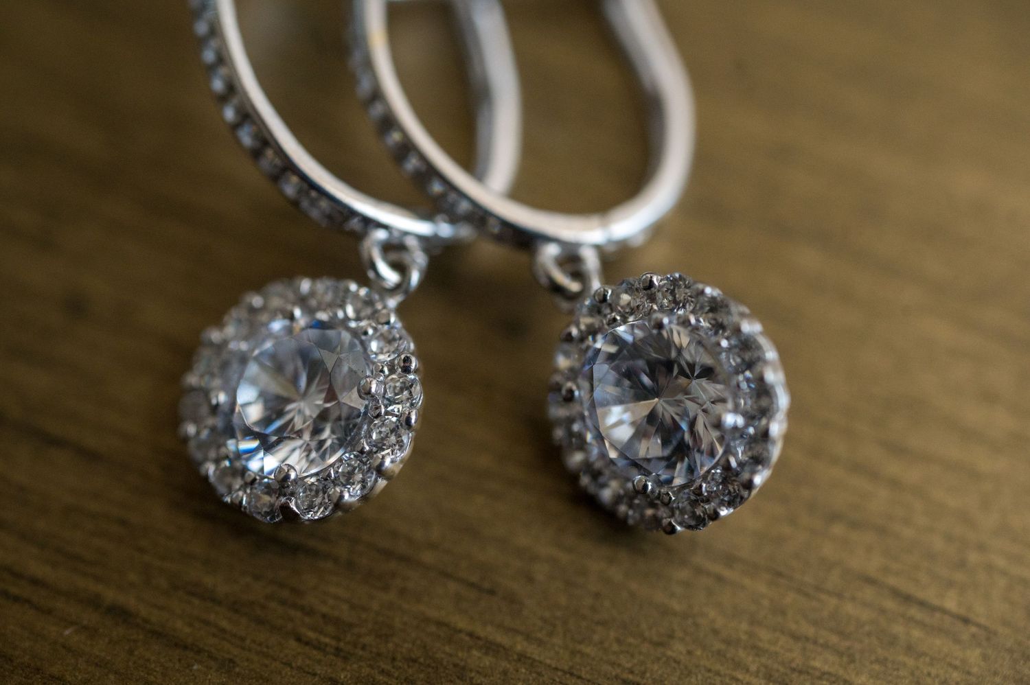 Elegant crystal drop earrings with intricate floral design sparkle on wooden surface.