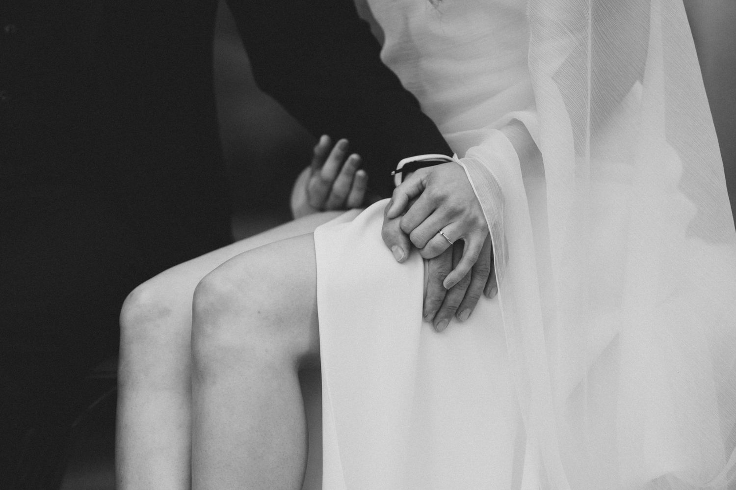 Close-up details of a white wedding dress against a dark background.