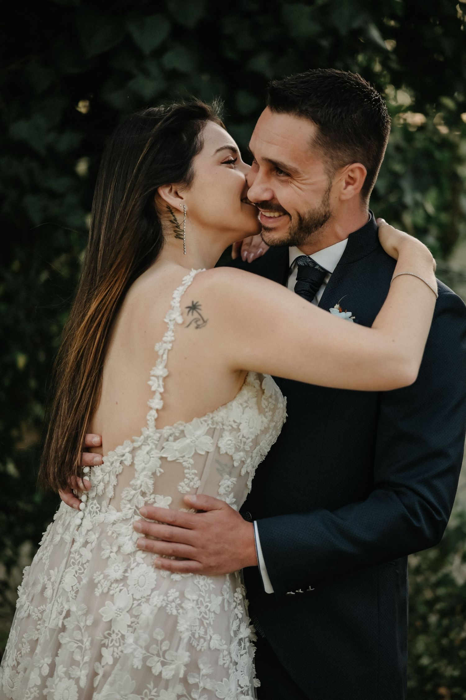A couple in wedding attire shares tender moments against a garden backdrop.