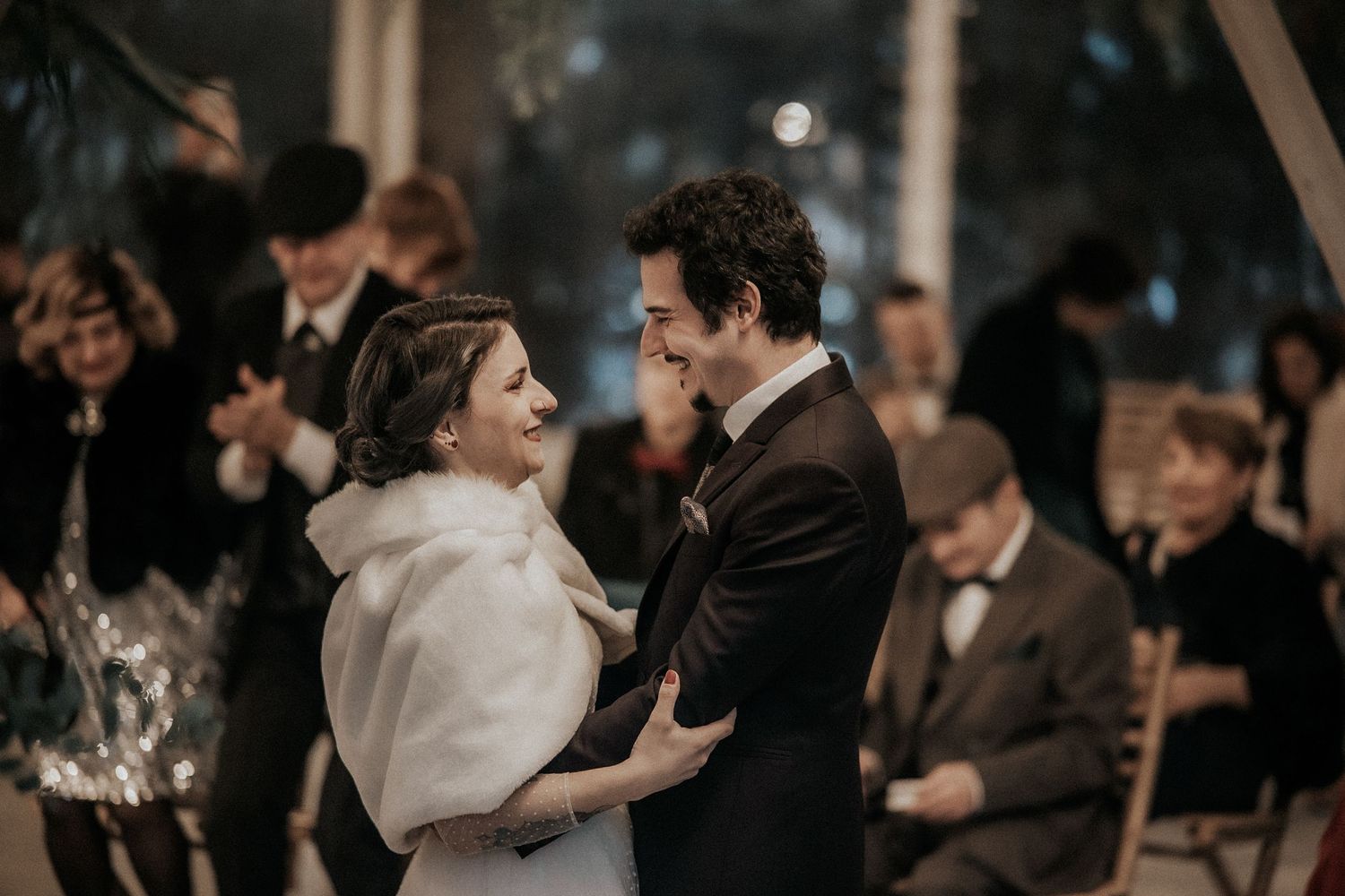 Wedding celebration at dusk with guests watching the newlyweds share a romantic moment.