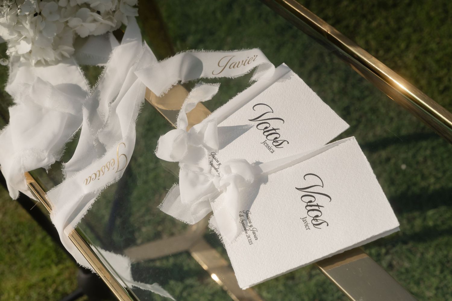 White paper wedding programs or cards displayed in a fanned arrangement on grass.