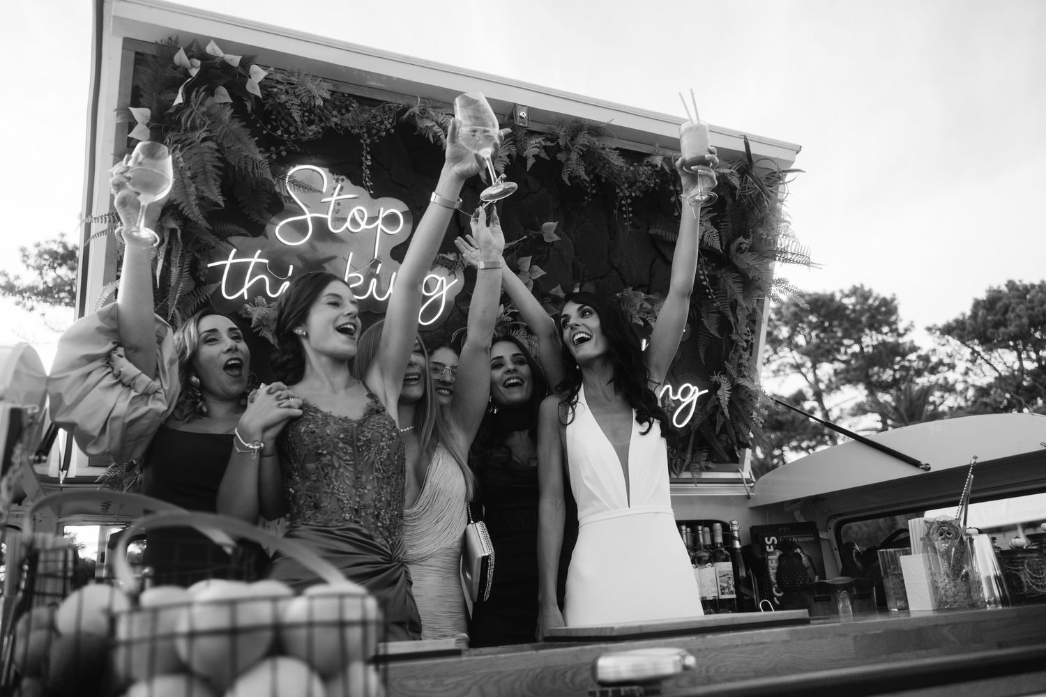 Wedding guests celebrate joyfully with raised hands during an outdoor reception.