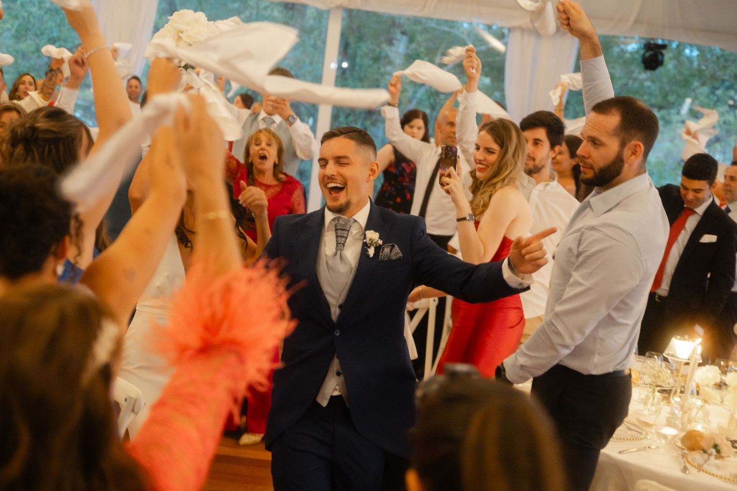 Wedding guests dance and celebrate together on a dance floor at an indoor reception venue.