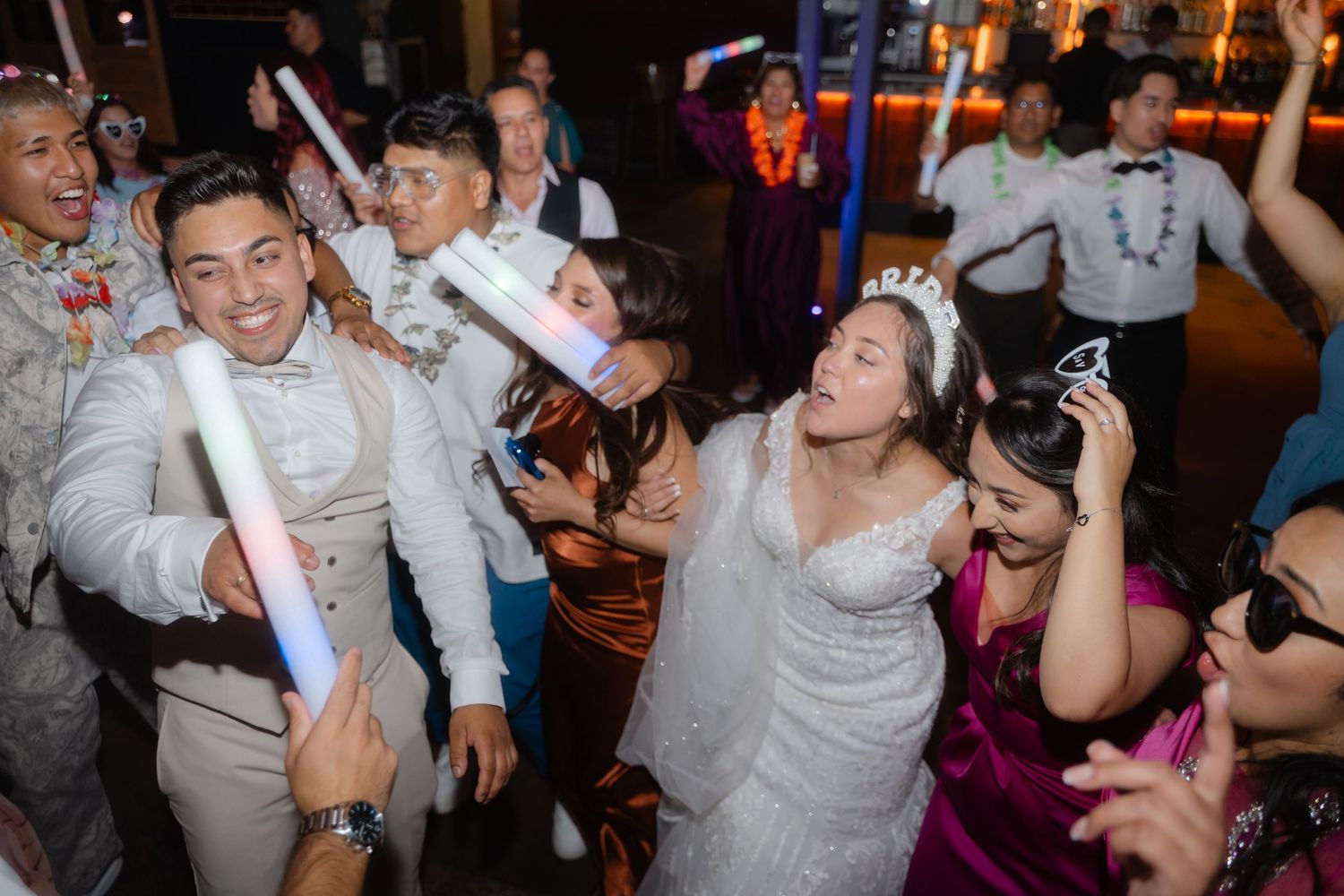 People dancing and celebrating with glowing pink and red light sticks at a nightclub party.