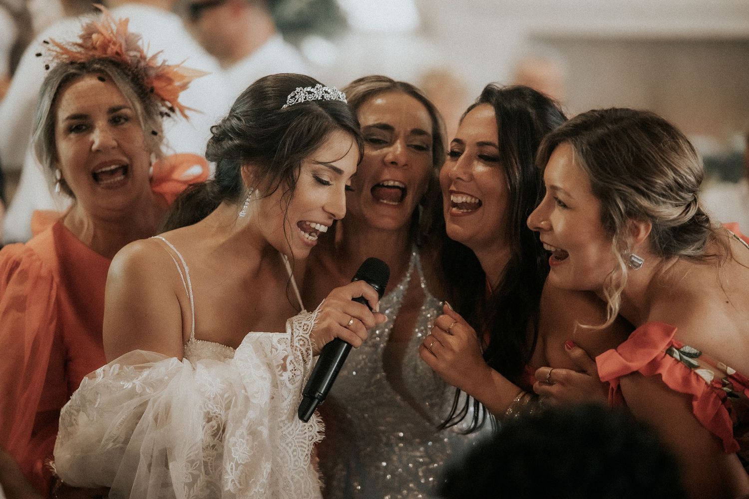 A joyful group of wedding guests share laughter and smiles during a celebratory moment at a reception.