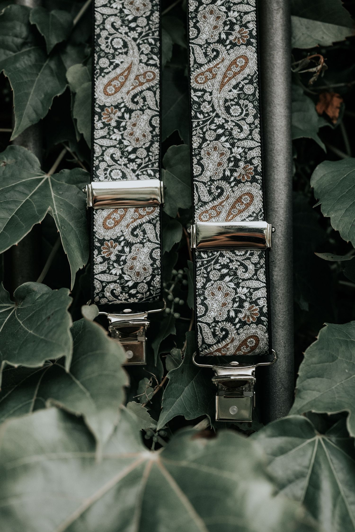 Metal gate bars with ornate vintage wallpaper pattern visible through them, framed by green ivy leaves.