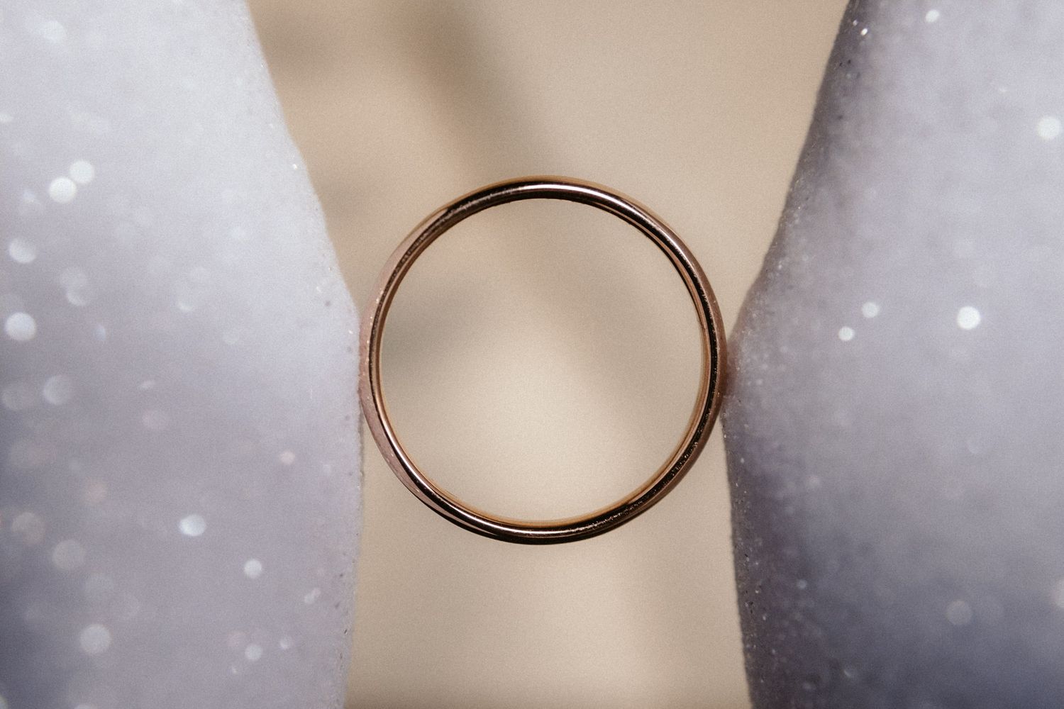 Seven rose gold wedding bands shown in sequence on a light beige background with bokeh lighting effects.