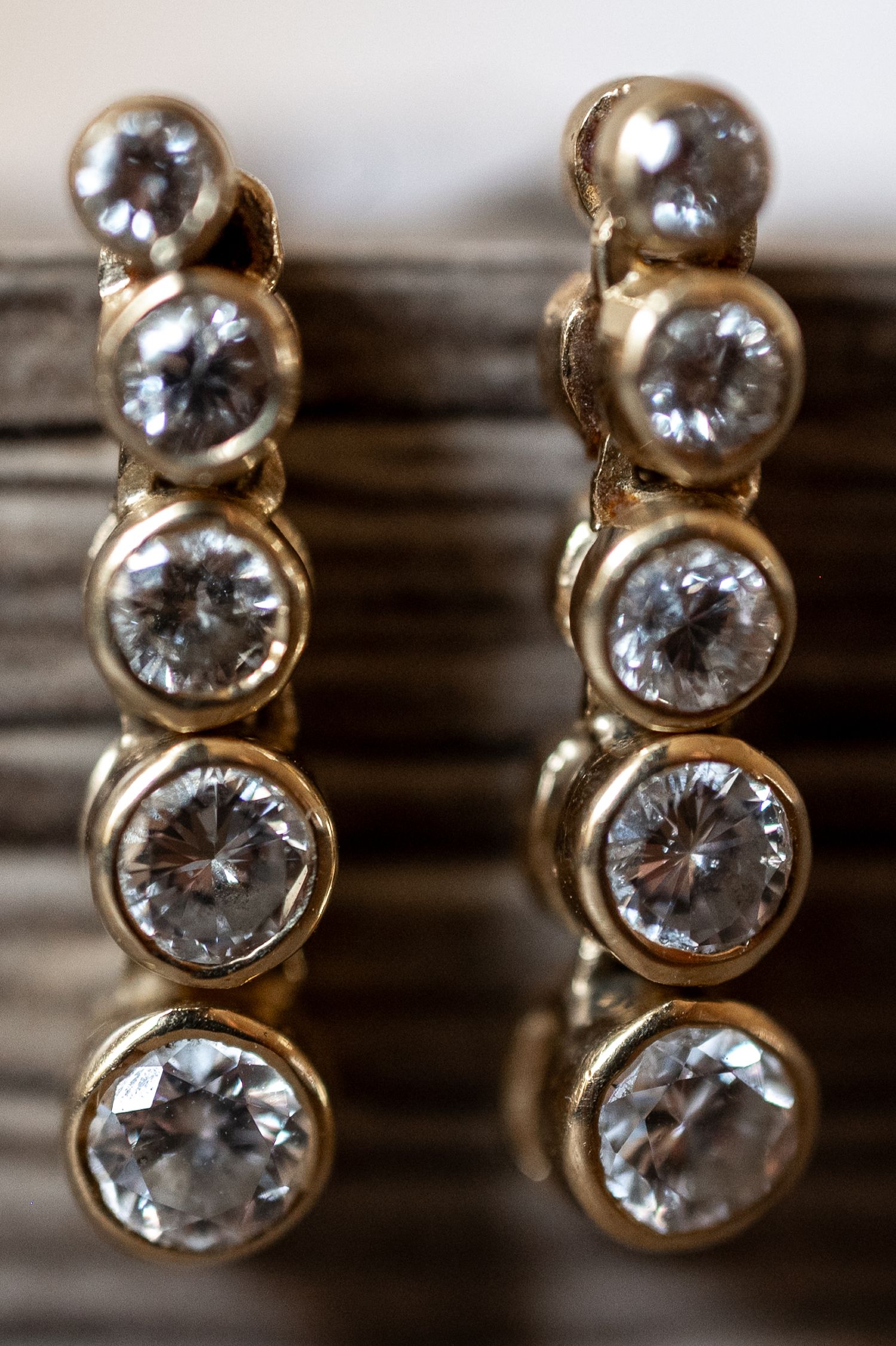 Close-up macro shot of sparkling diamond stud earrings with gold settings in a row.
