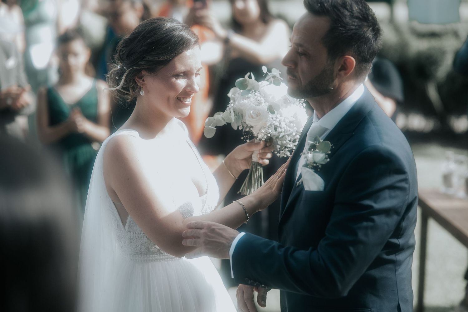 A couple shares an intimate moment during their wedding ceremony with soft natural lighting in the background.