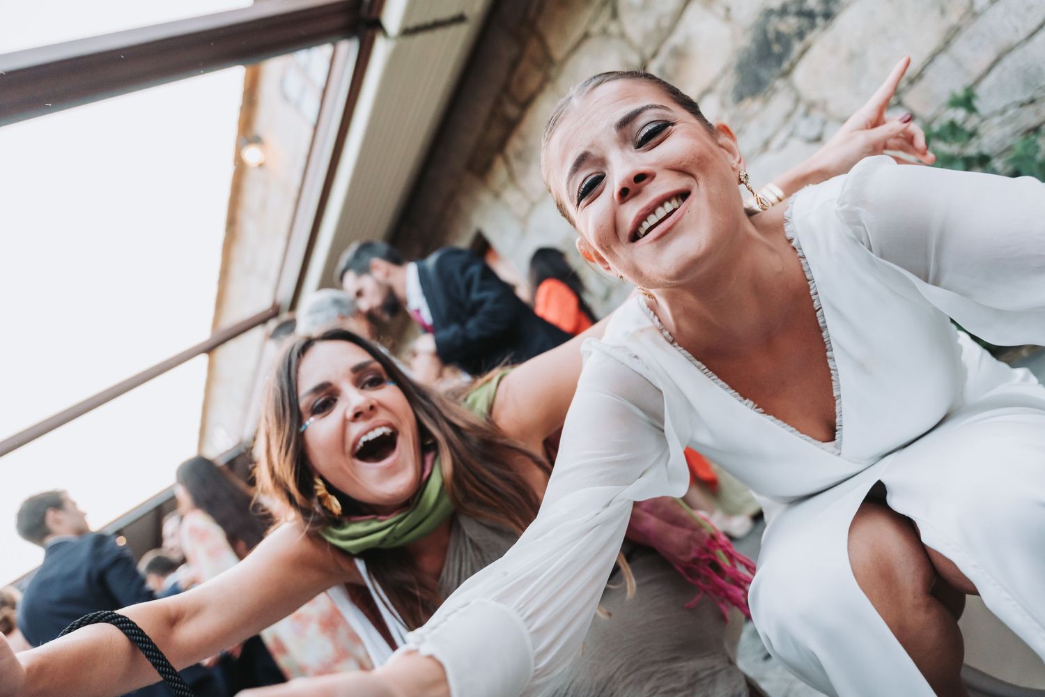 A joyful moment captured at a wedding celebration with people laughing and embracing.
