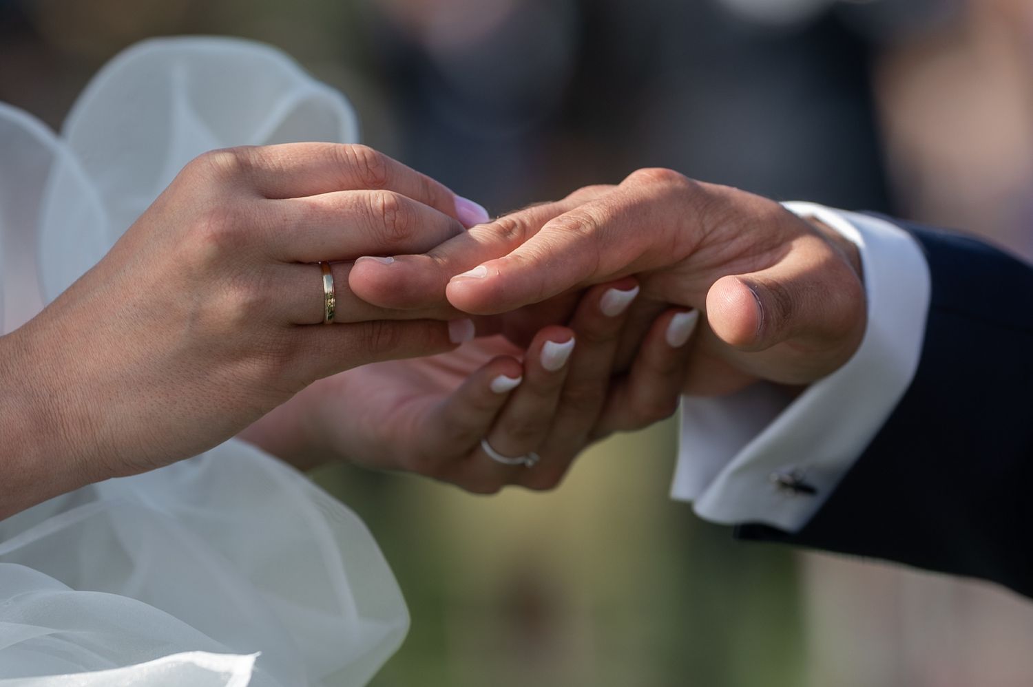 Close-up view of hands exchanging wedding rings during a traditional marriage ceremony.
