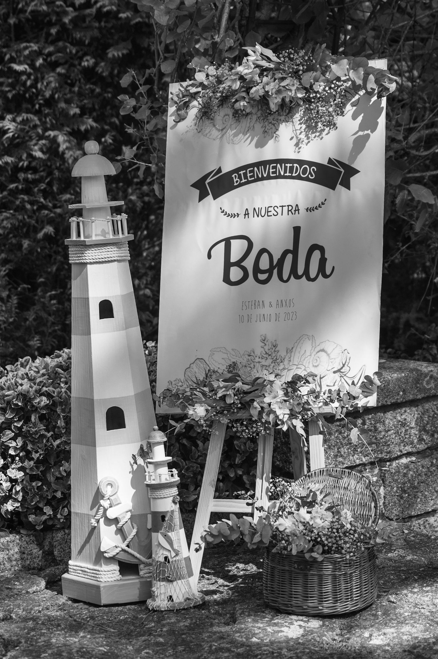 A series of decorative white lighthouse structures and welcome signs arranged for a wedding celebration in a garden setting.