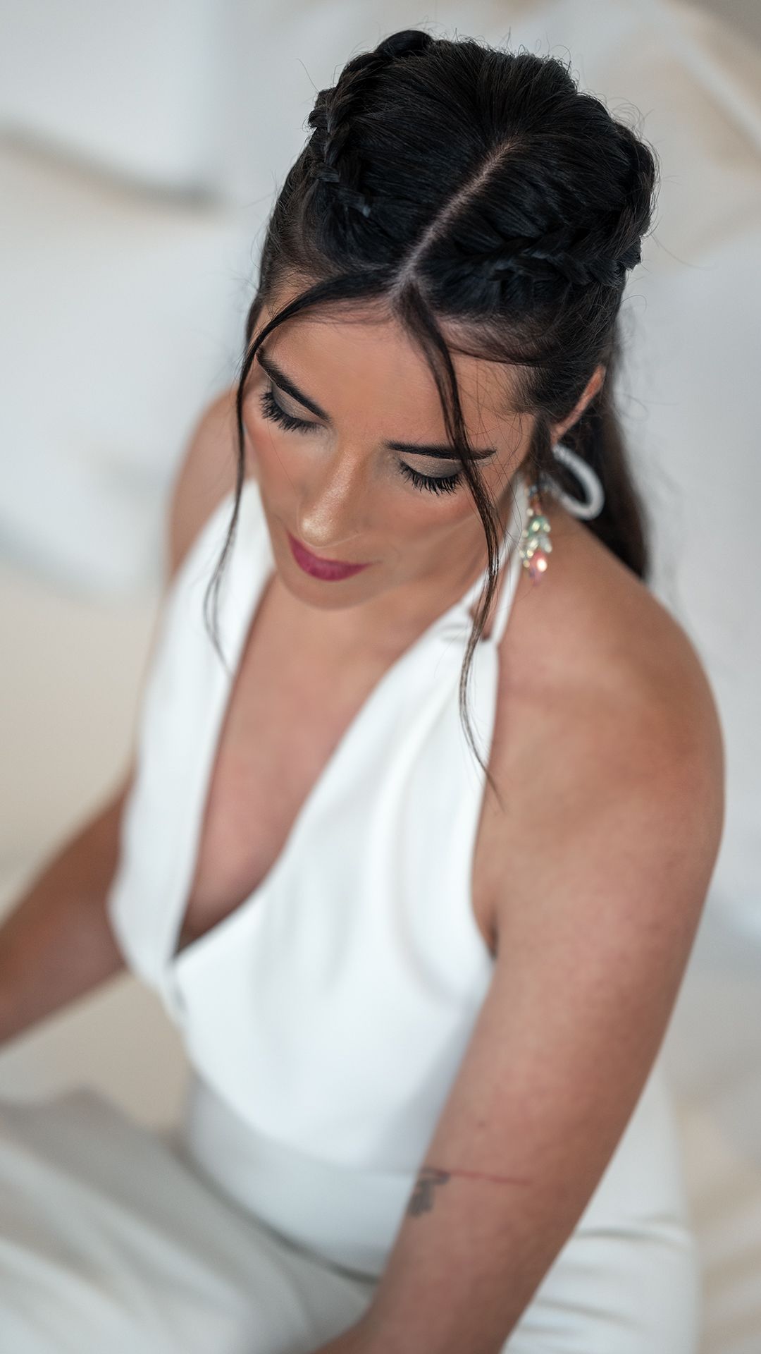A bride in a white wedding dress with dark hair and elegant makeup looks down in a series of intimate portrait shots.