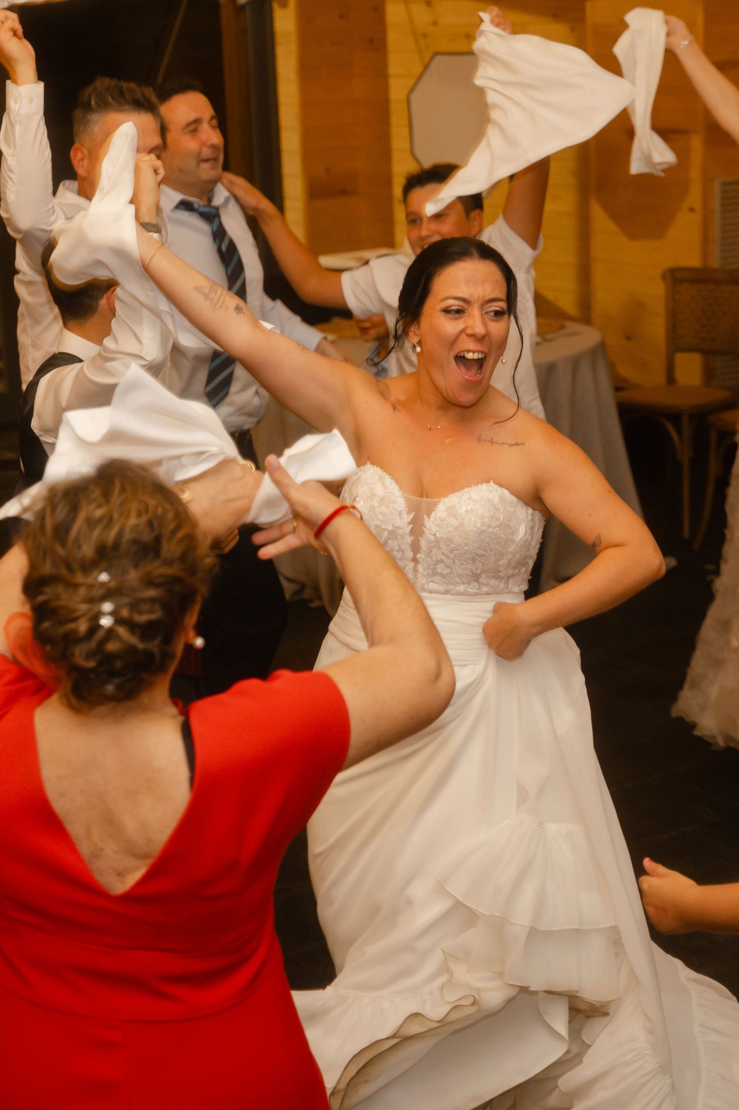 Wedding celebration showing people dancing and waving white napkins in a joyful moment at an indoor reception.