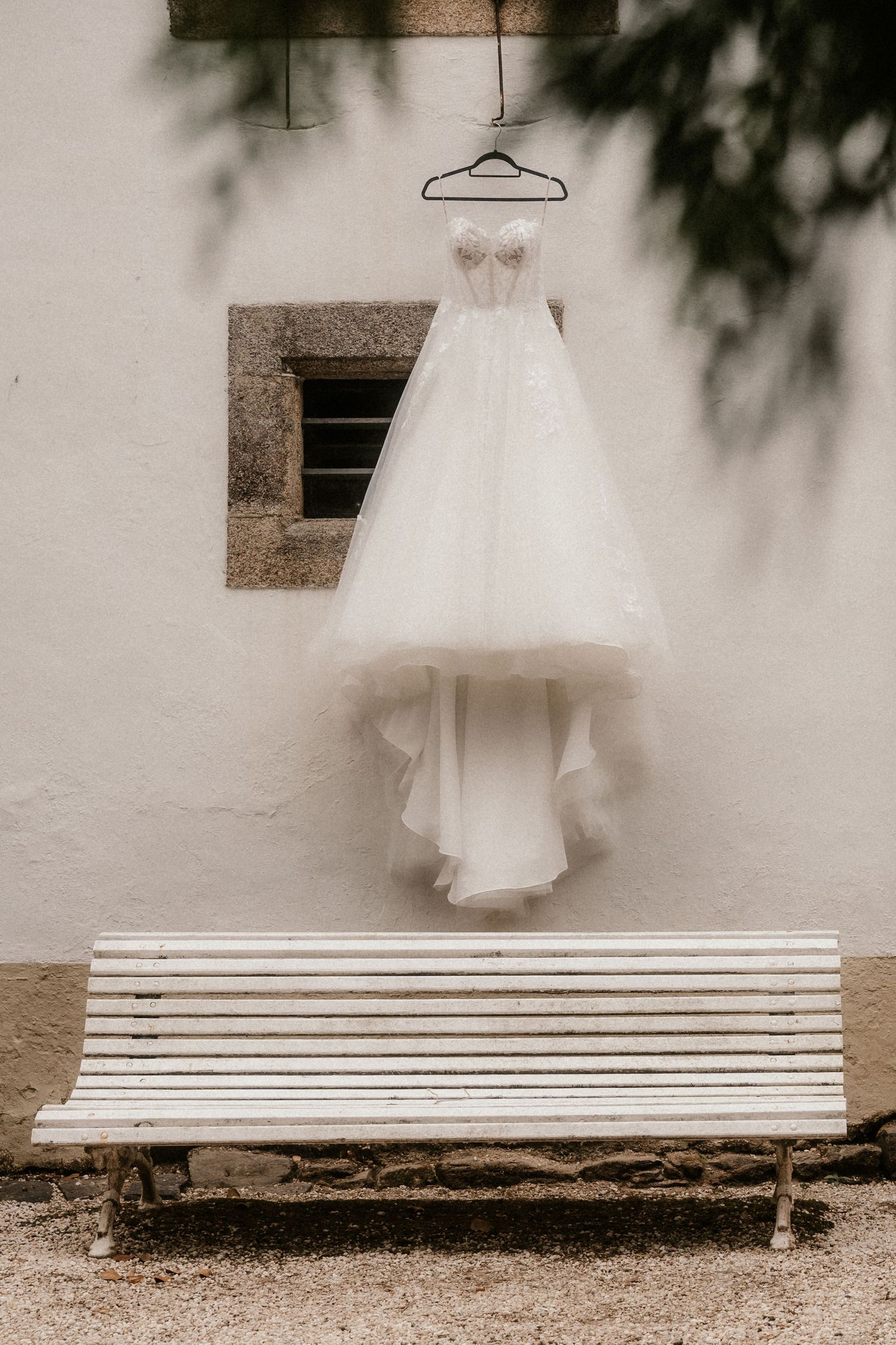 A dreamy sepia-toned triptych shows a white wedding dress floating against a white wall above a garden bench.