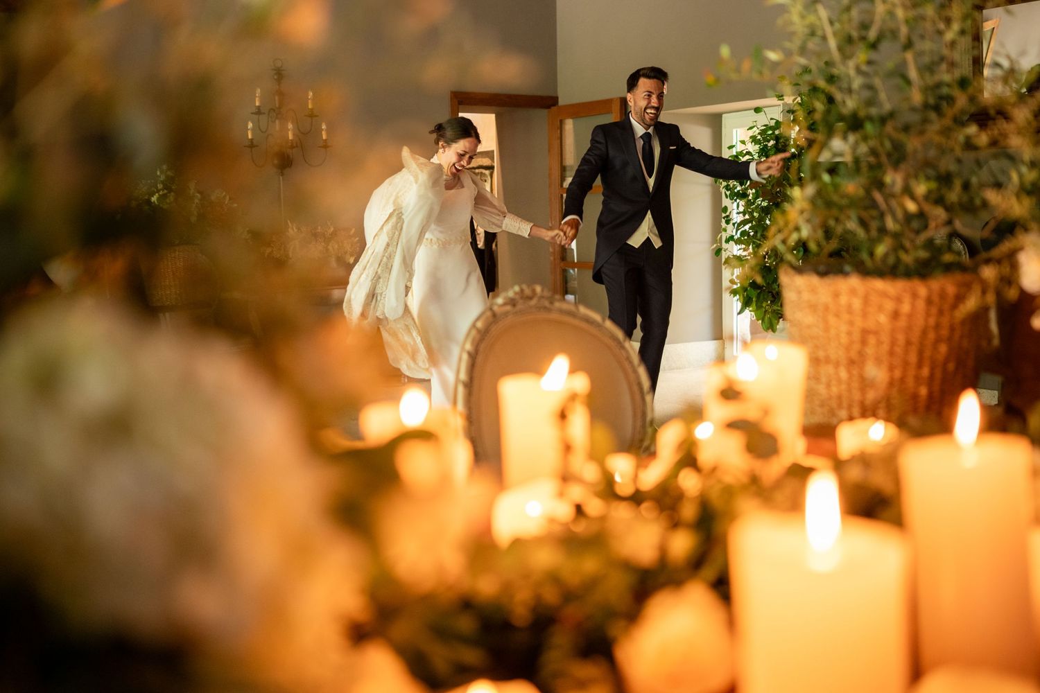 A romantic candlelit wedding reception table decorated with lush greenery and glowing candles creates an intimate atmosphere.