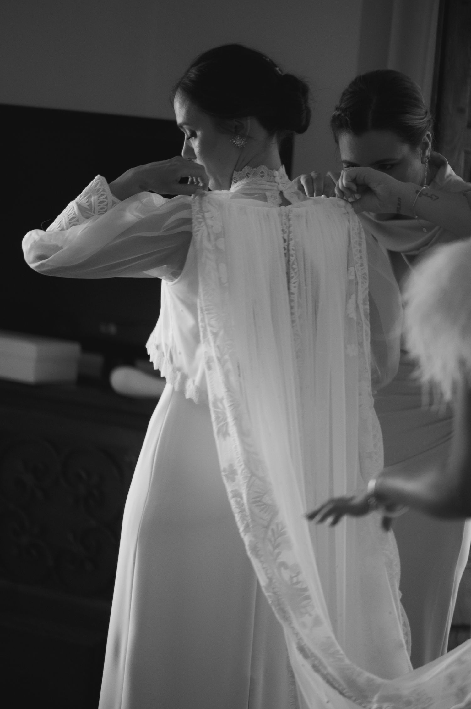 A close-up view of an elegant white wedding dress with delicate lace details being fastened.