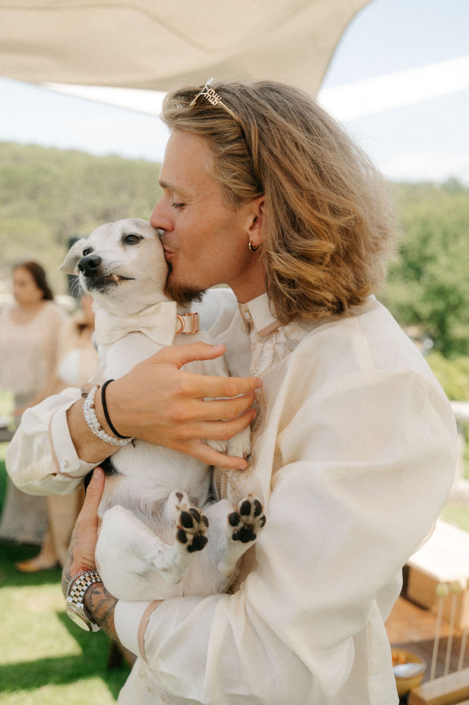 A series of candid moments showing a person in white holding and sharing affectionate moments with a white dog outdoors.