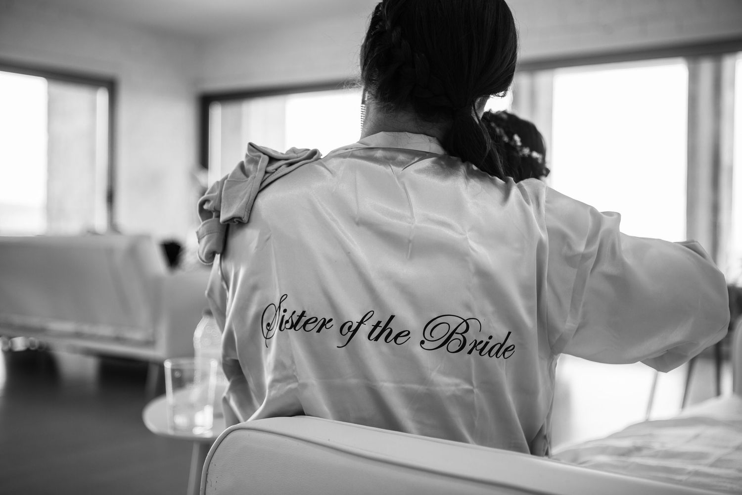 Black and white photo showing satin robe with 'Sister of the Bride' embroidered text on the back.