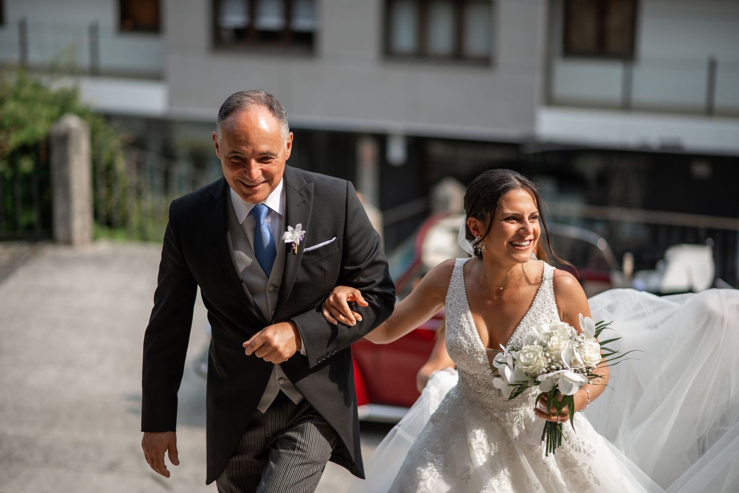 A wedding couple poses for portraits on a sunny day near modern buildings.