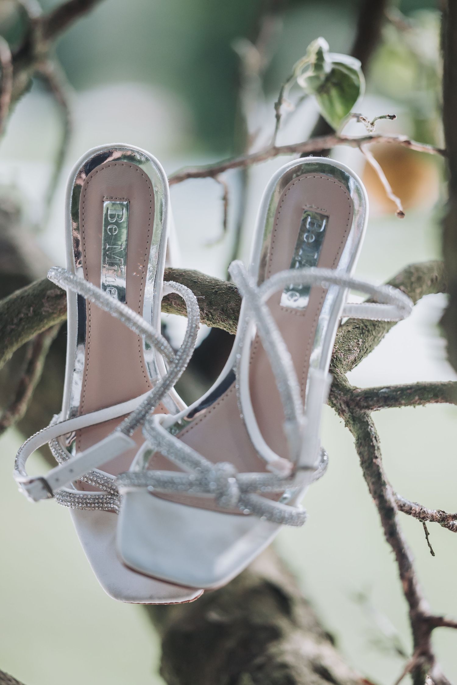 Elegant white strappy bridal sandals with delicate details displayed on a light background.