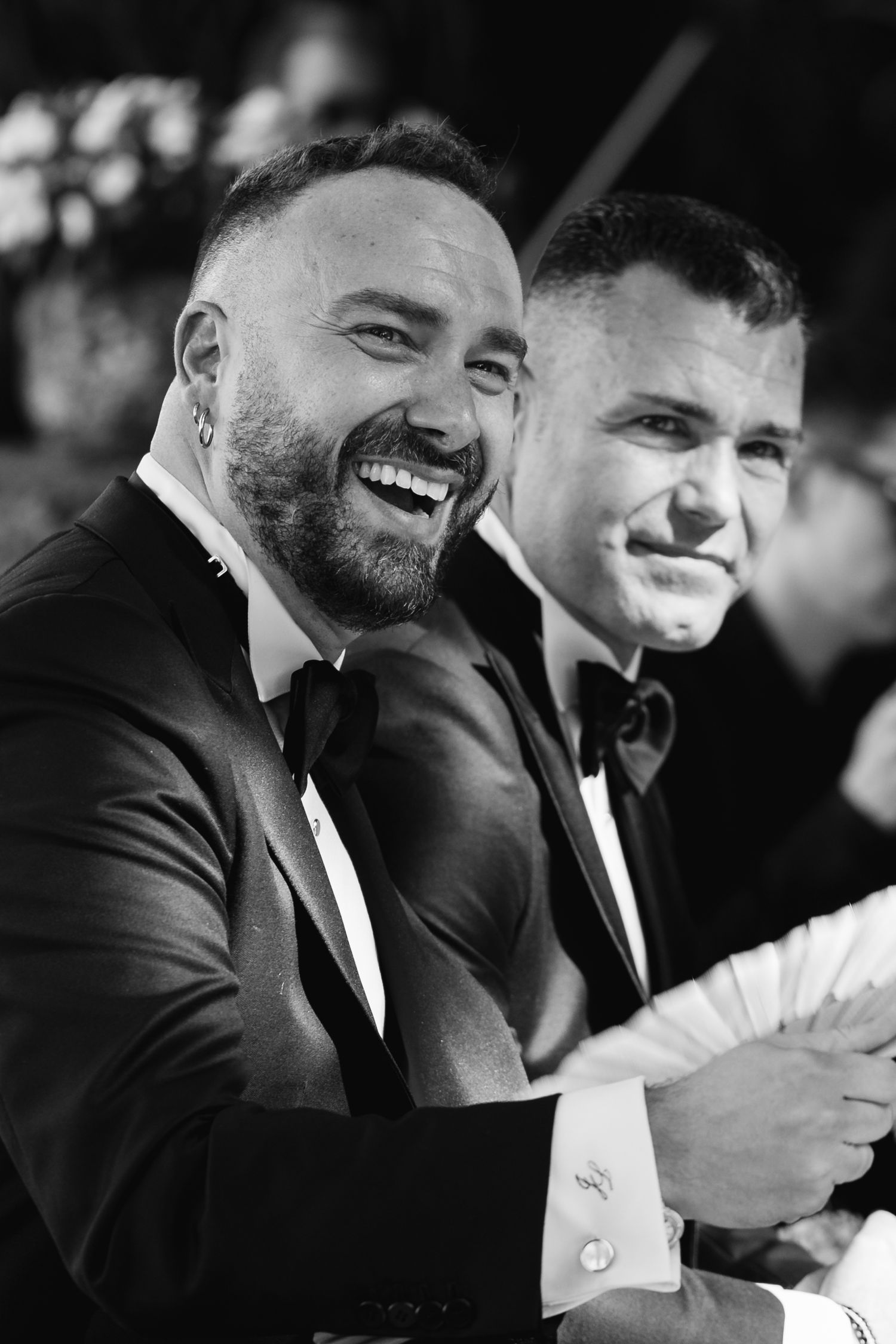 Black and white candid photos show two men in tuxedos sharing genuine laughter together.