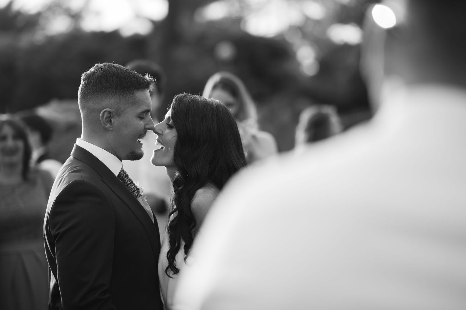 Black and white wedding photo sequence showing a romantic kiss between newlyweds at their ceremony.