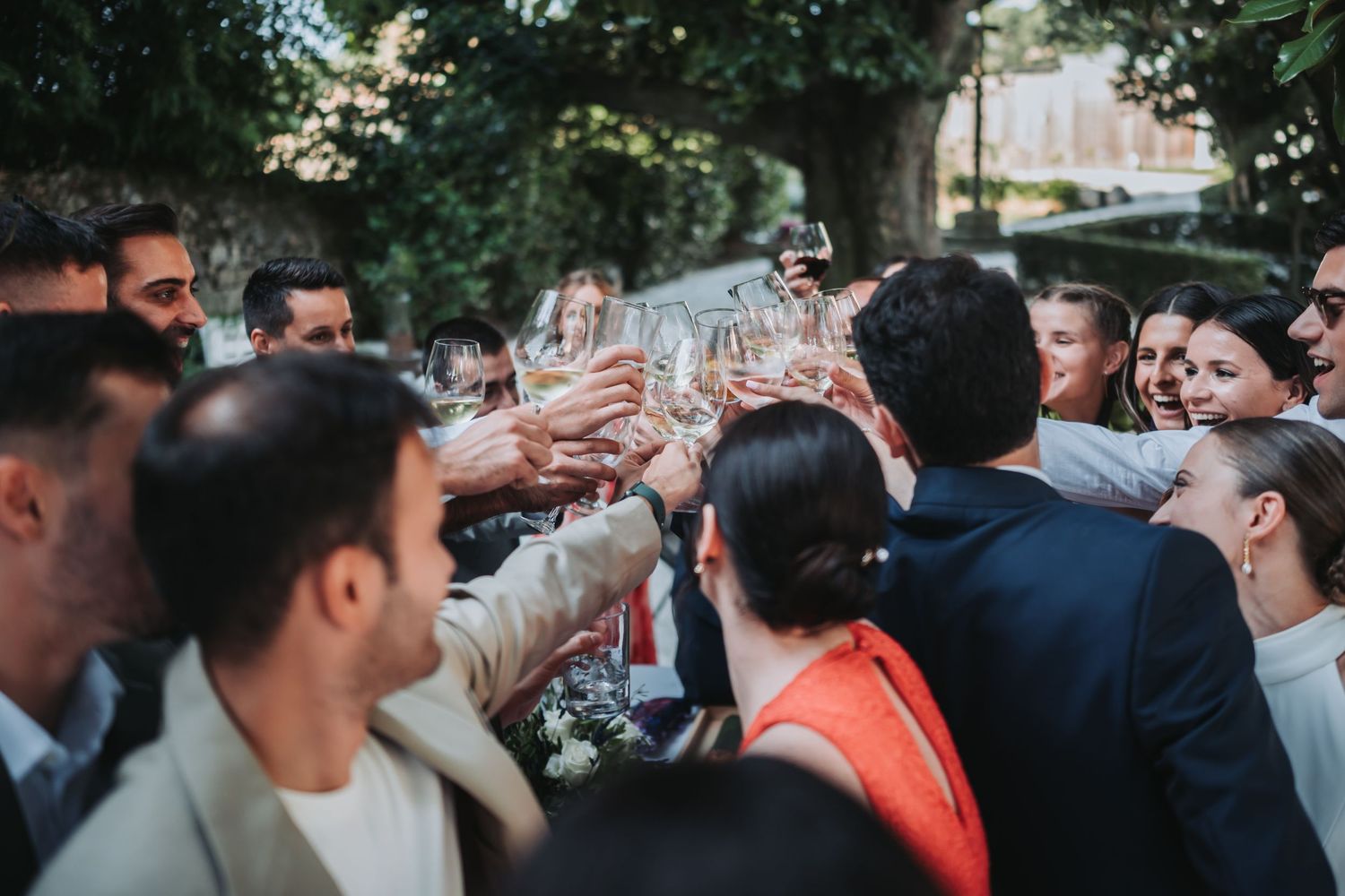 Wedding guests gather outdoors in a celebratory moment during a summer reception.