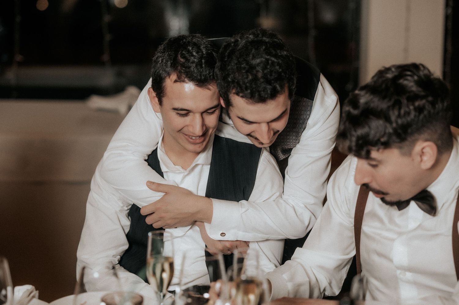 Wedding guests in white shirts gather around a table during a celebration event.