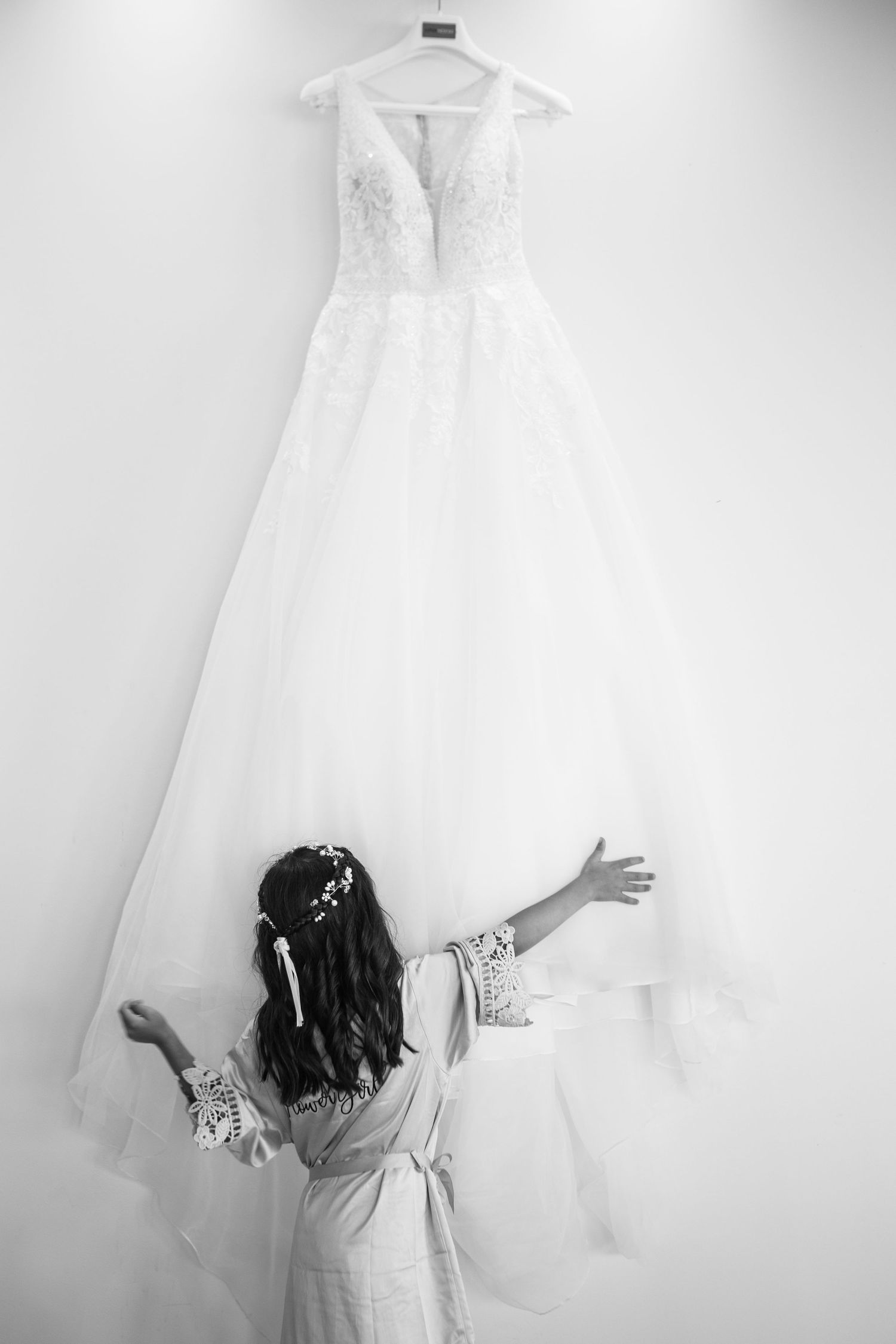A series of black and white photos showing a white wedding dress displayed against a light wall.
