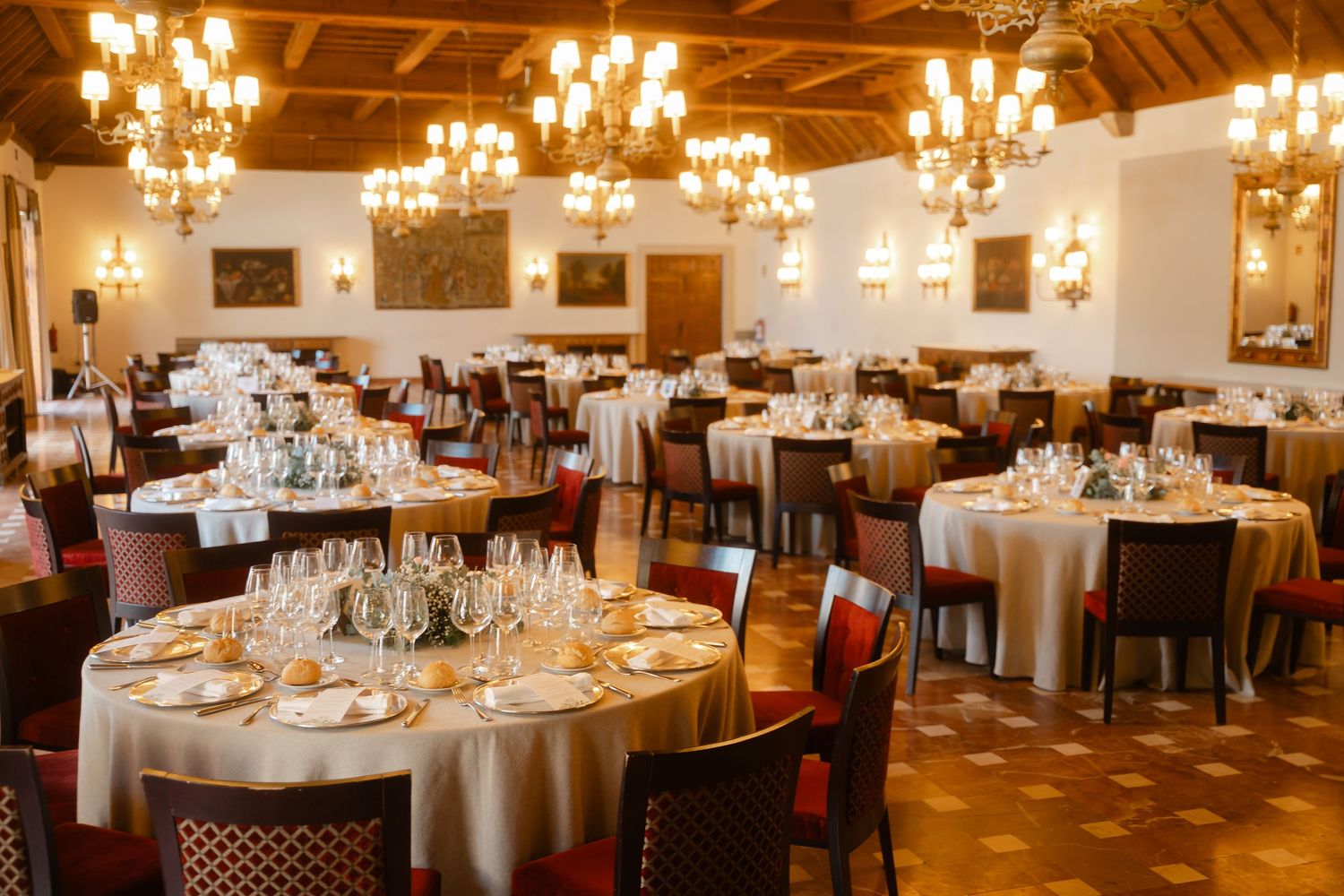 Elegant banquet hall with crystal chandeliers and round tables set for a formal dinner reception.