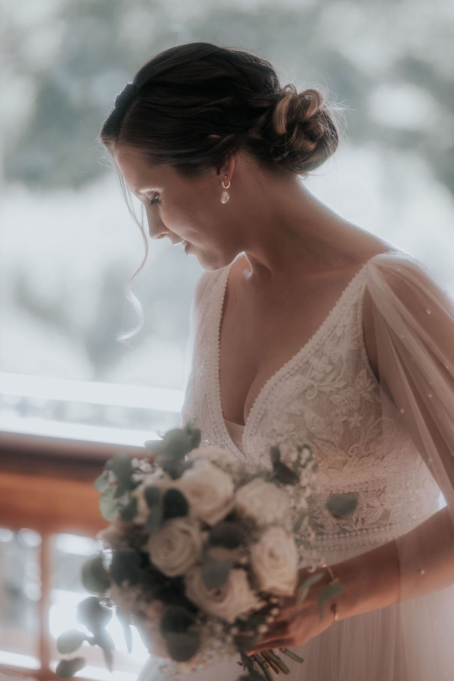 A dreamy bridal portrait showing delicate lace details and a soft white bouquet against a blurred background.