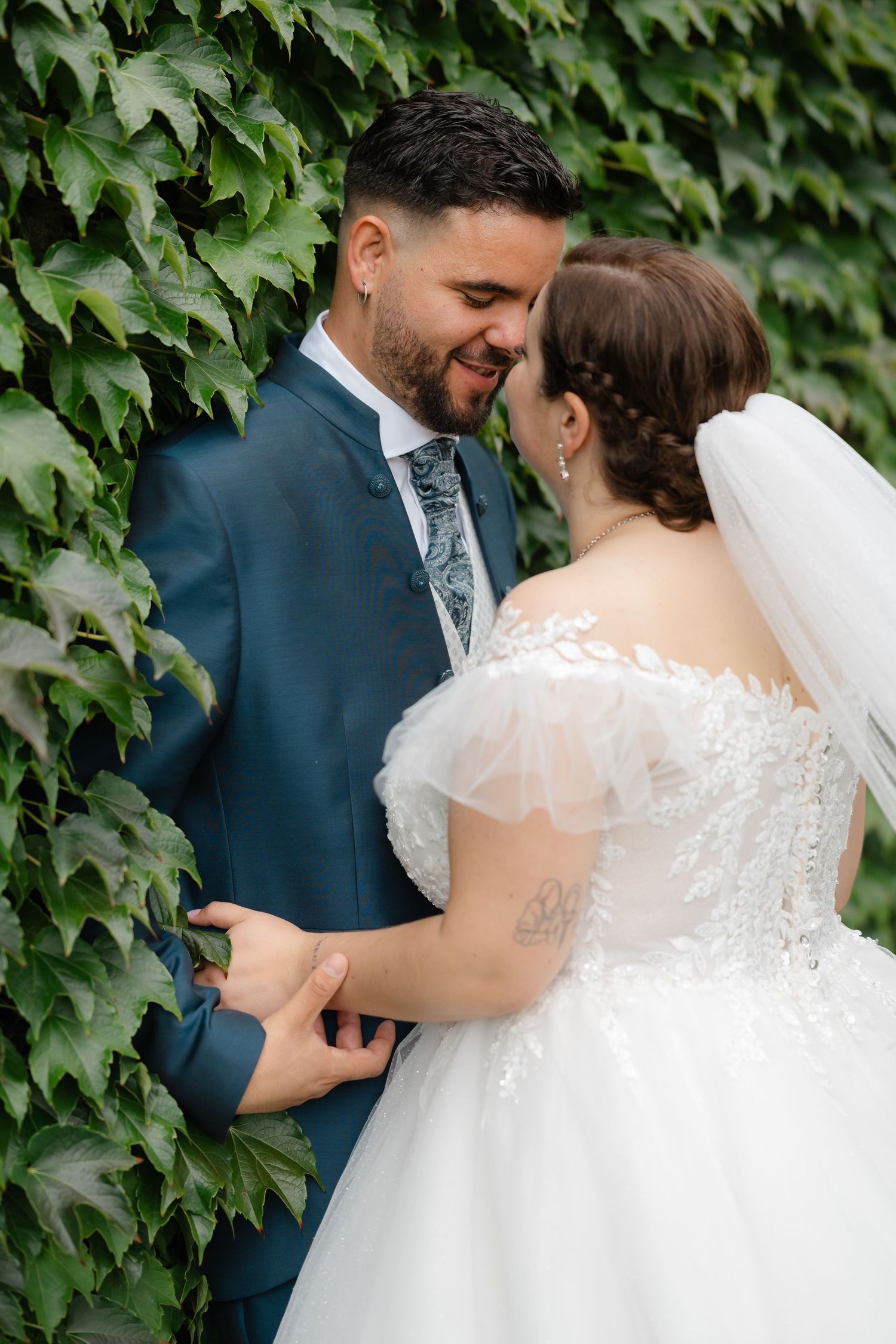 Intimate wedding portraits against a backdrop of lush green ivy showing joyful moments between the couple.