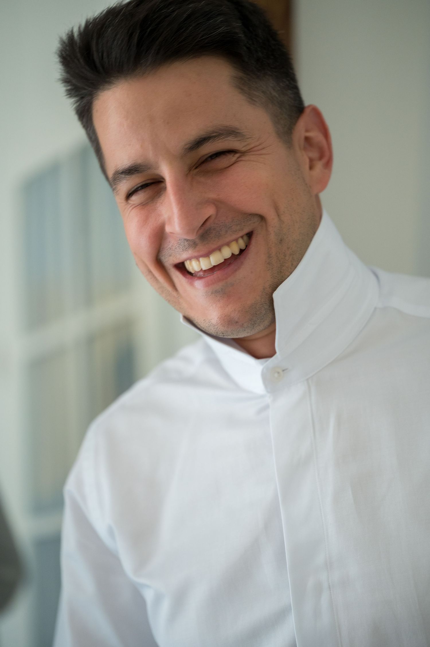 A series of four photos showing someone in a white shirt smiling and laughing against a light background.