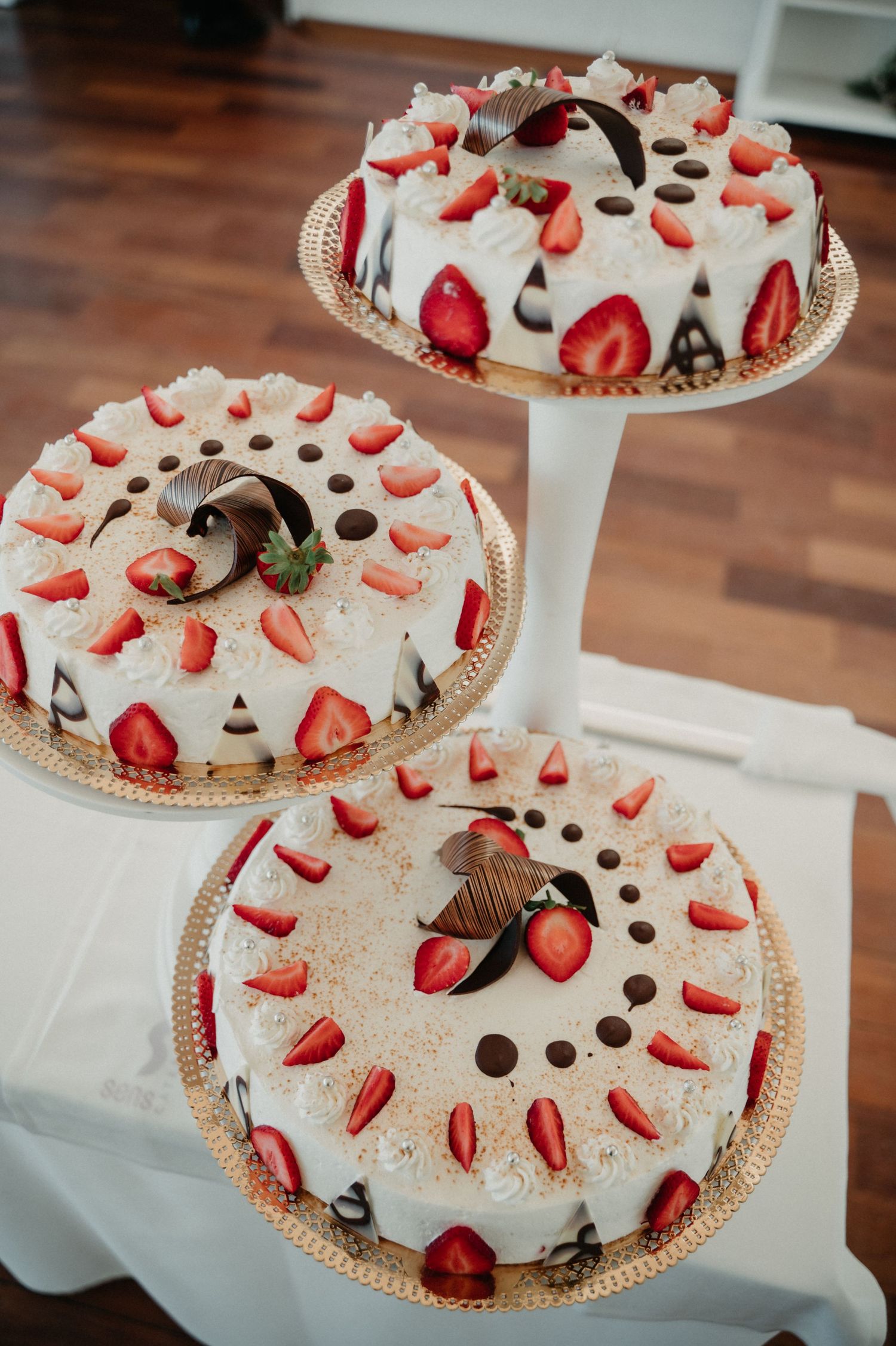 White cream pie decorated with fresh strawberry slices and chocolate pieces arranged in a circular pattern on a glass plate.