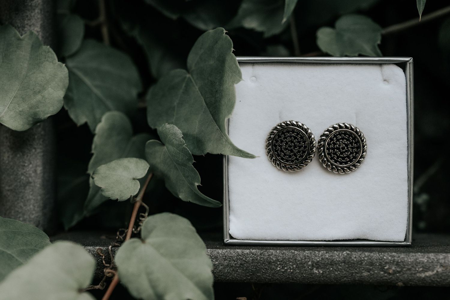 Antique-style oxidized silver stud earrings with intricate floral patterns displayed on a white surface.
