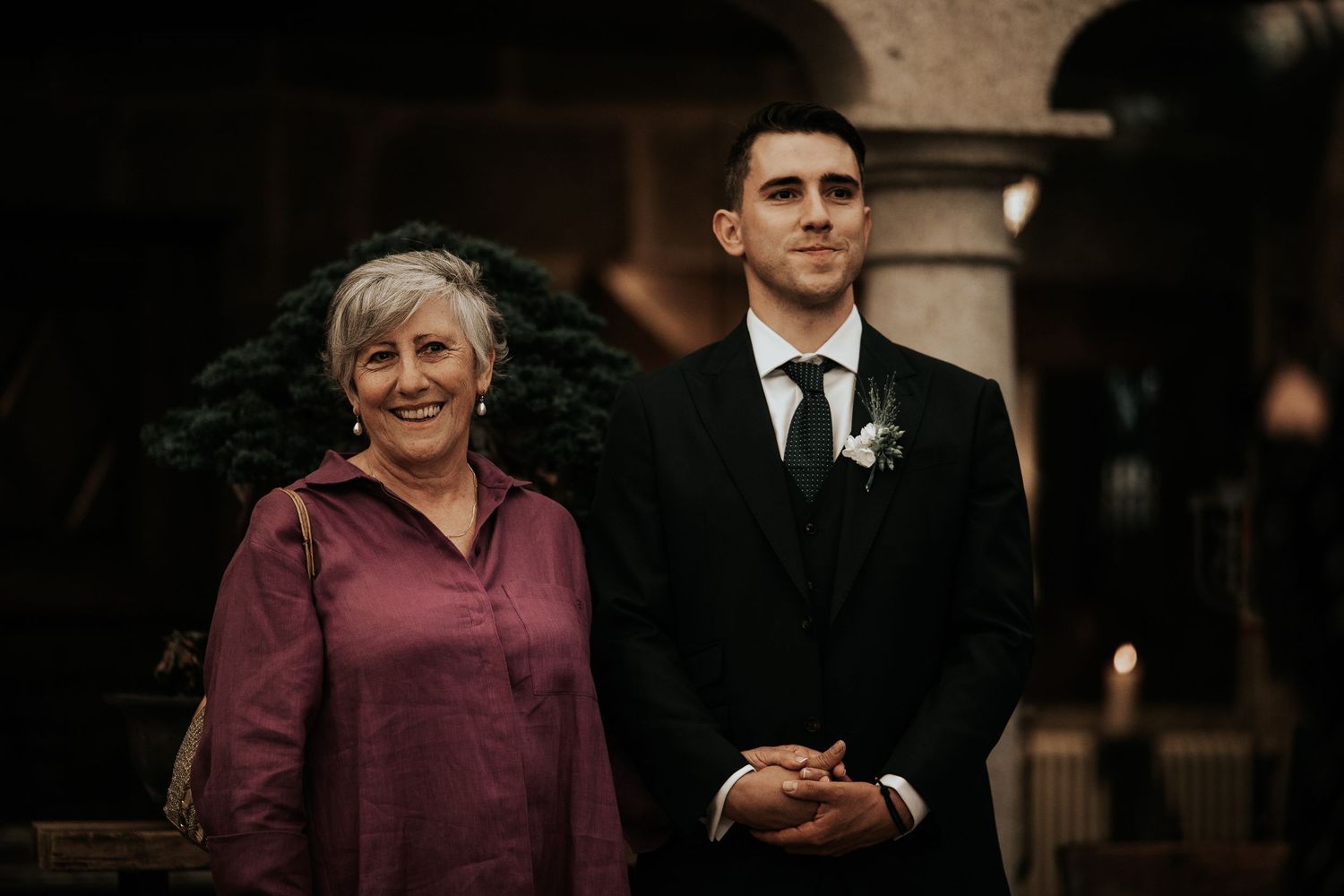 Wedding guests in burgundy attire gather together at an elegant indoor venue during a formal celebration.
