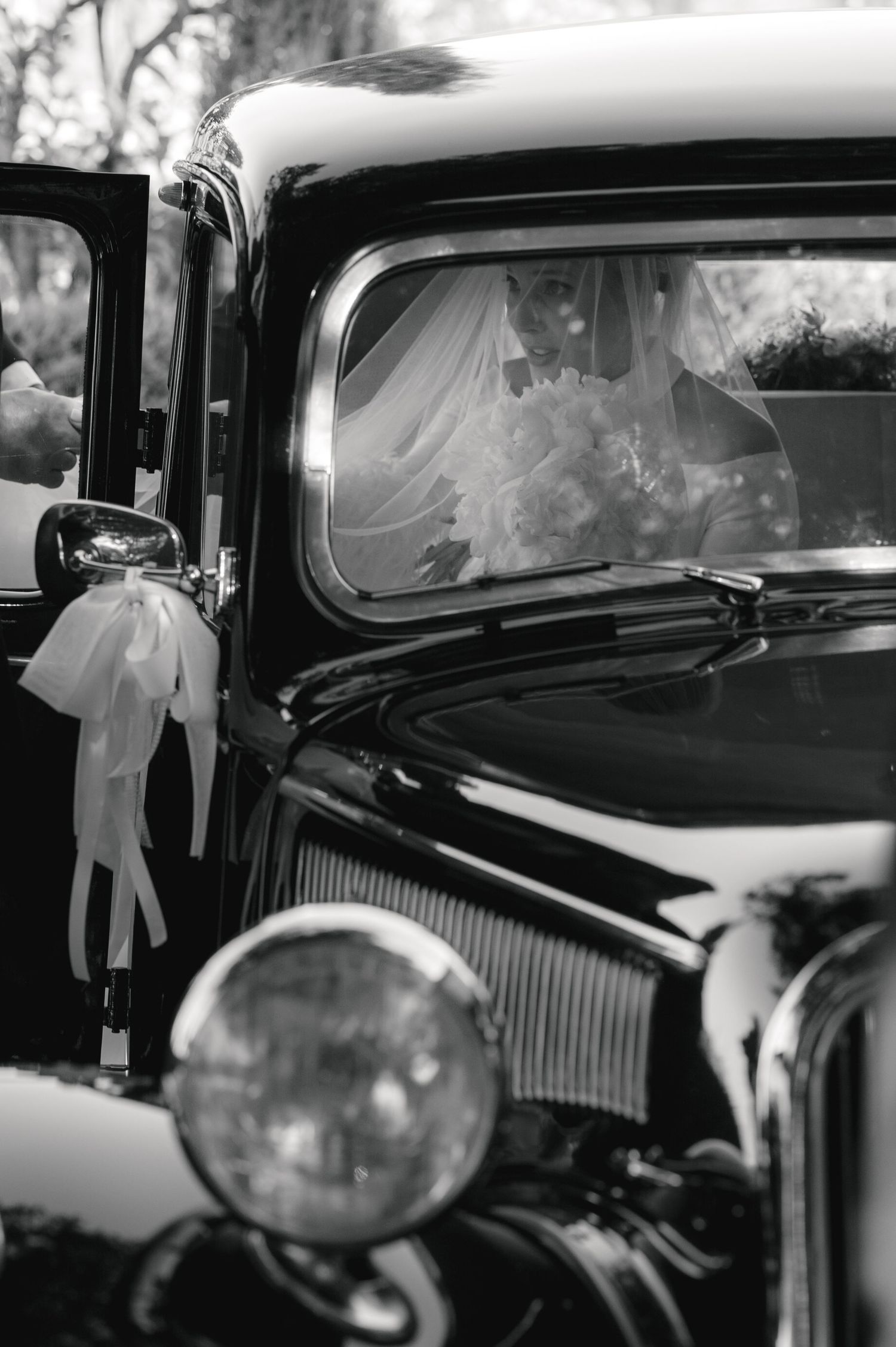 Classic vintage black car decorated with white ribbons and bows for a wedding ceremony.