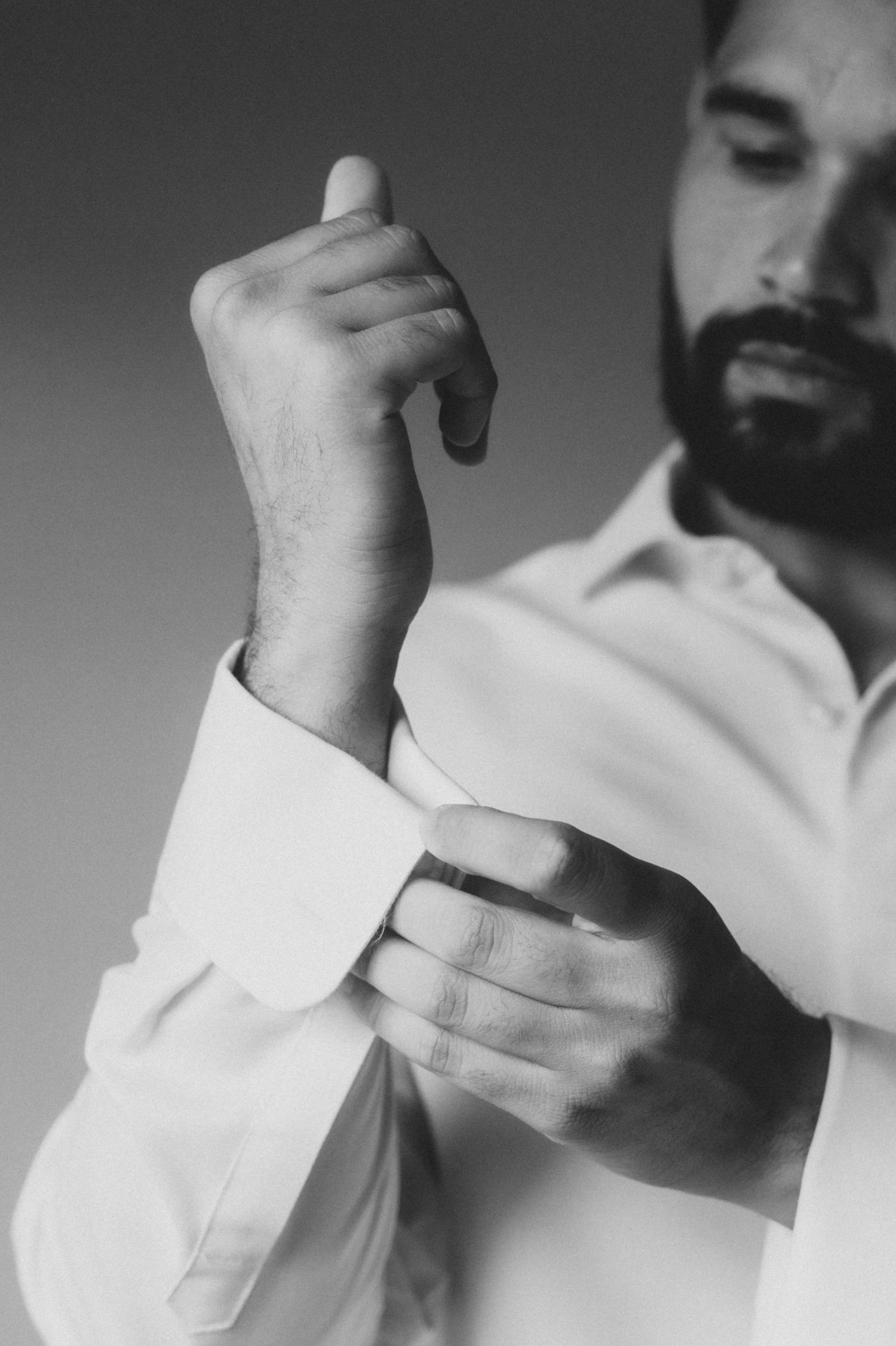 A sequence of black and white photos showing hands adjusting a white dress shirt sleeve cuff.