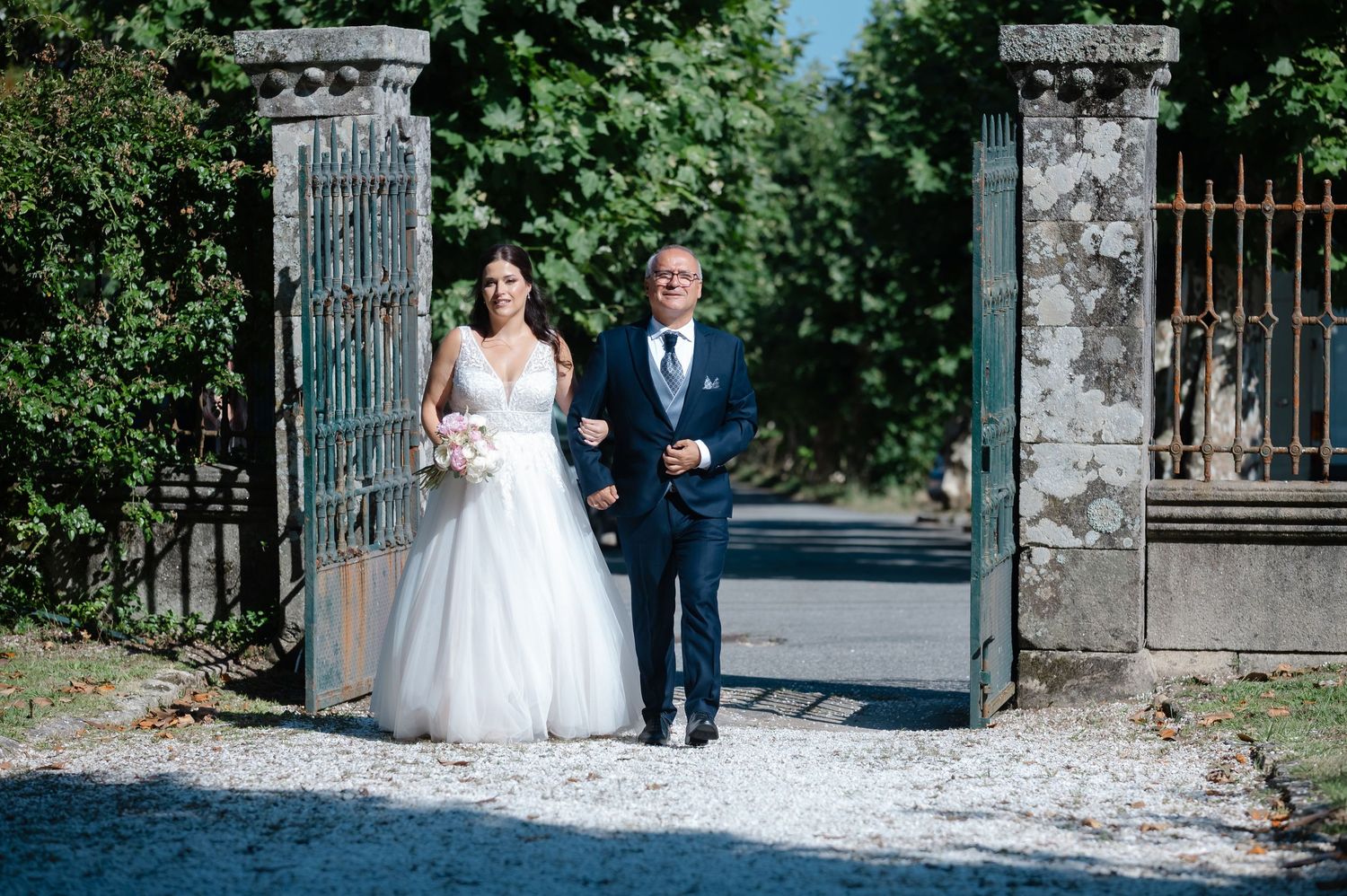 Wedding ceremony entrance with ornate metal gates and stone walls in a garden setting.